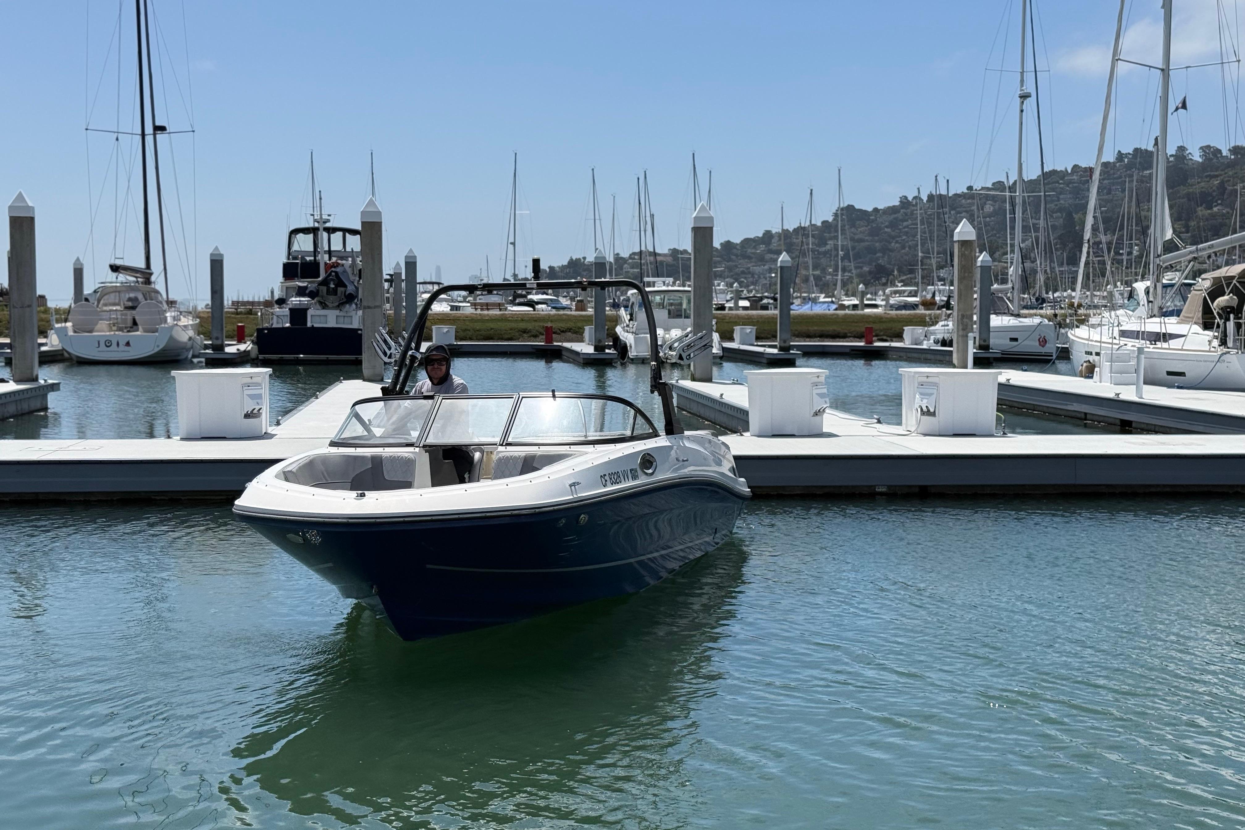 2021 Bayliner VR5 Bowrider I/O docked at a marina with sailboats in the background.