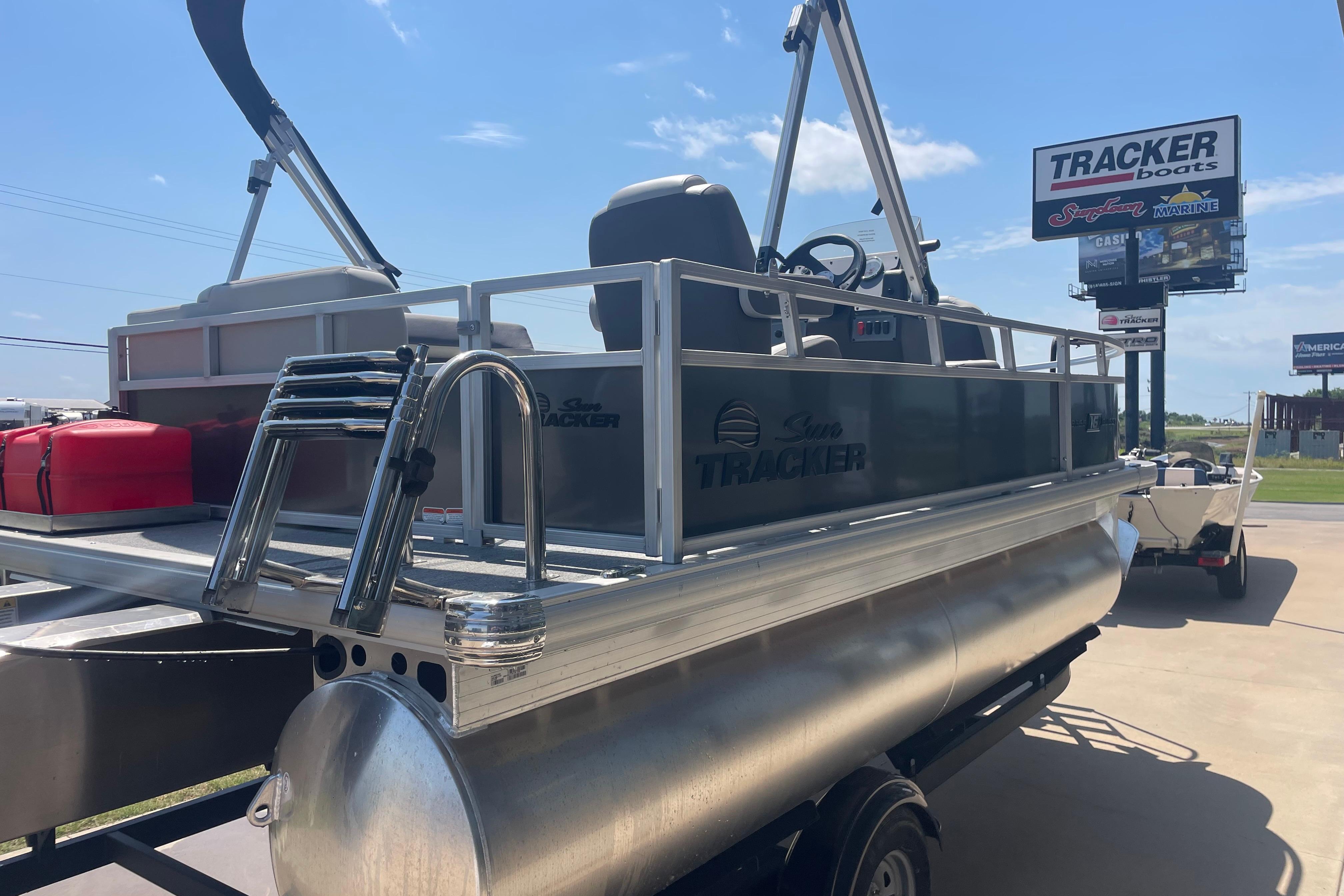 2026 Sun Tracker Bass Buggy 16 XL Select pontoon boat at dealership under clear blue sky.