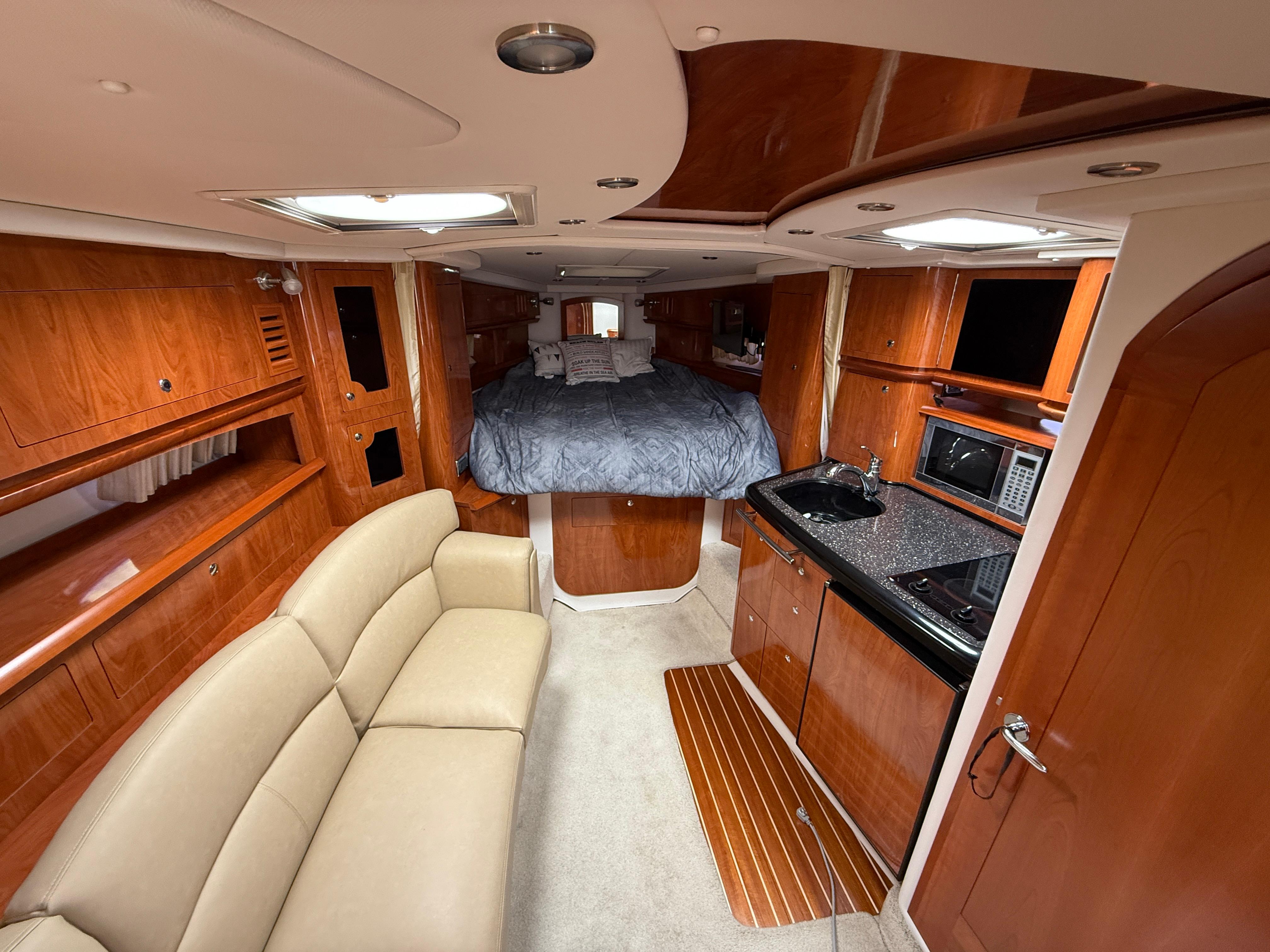 Luxurious 2008 Four Winns V358 yacht interior with wood finish, kitchenette, and cozy sleeping area.