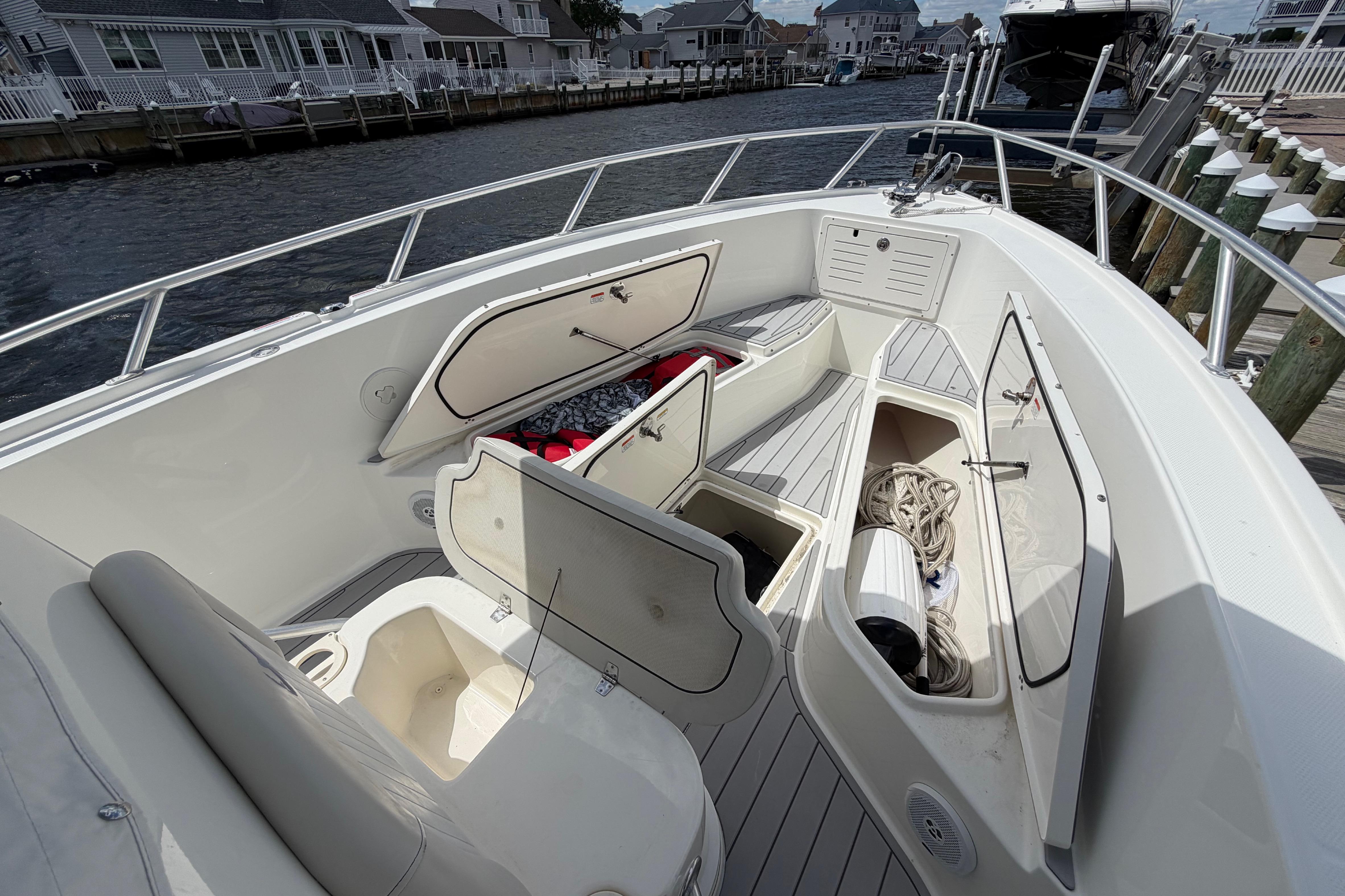 2017 Mako 284 Center Console boat with open storage compartments, docked by waterfront homes.