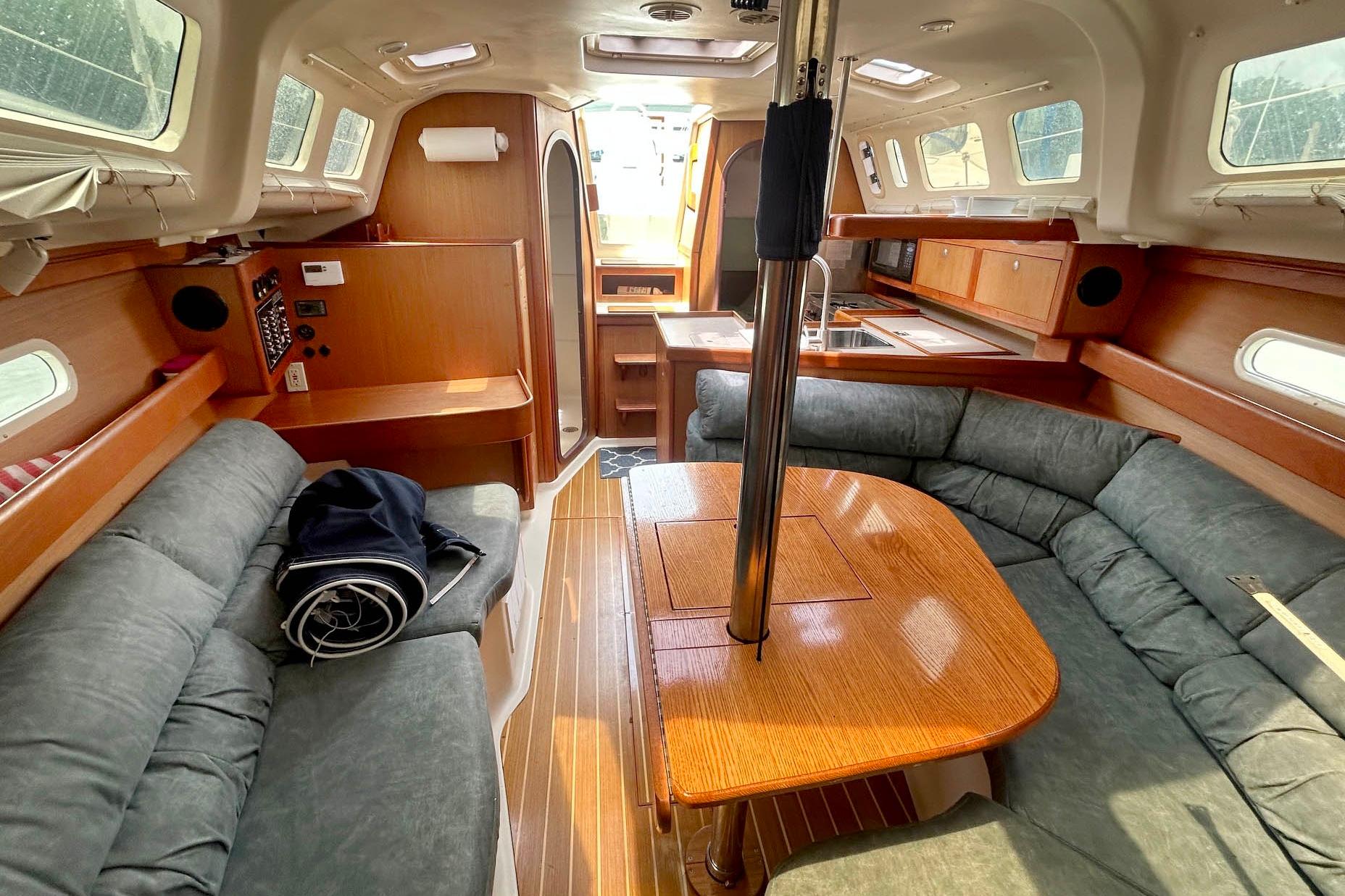 Interior of a 1998 Hunter 340 sailboat with cozy seating and wooden finishes.