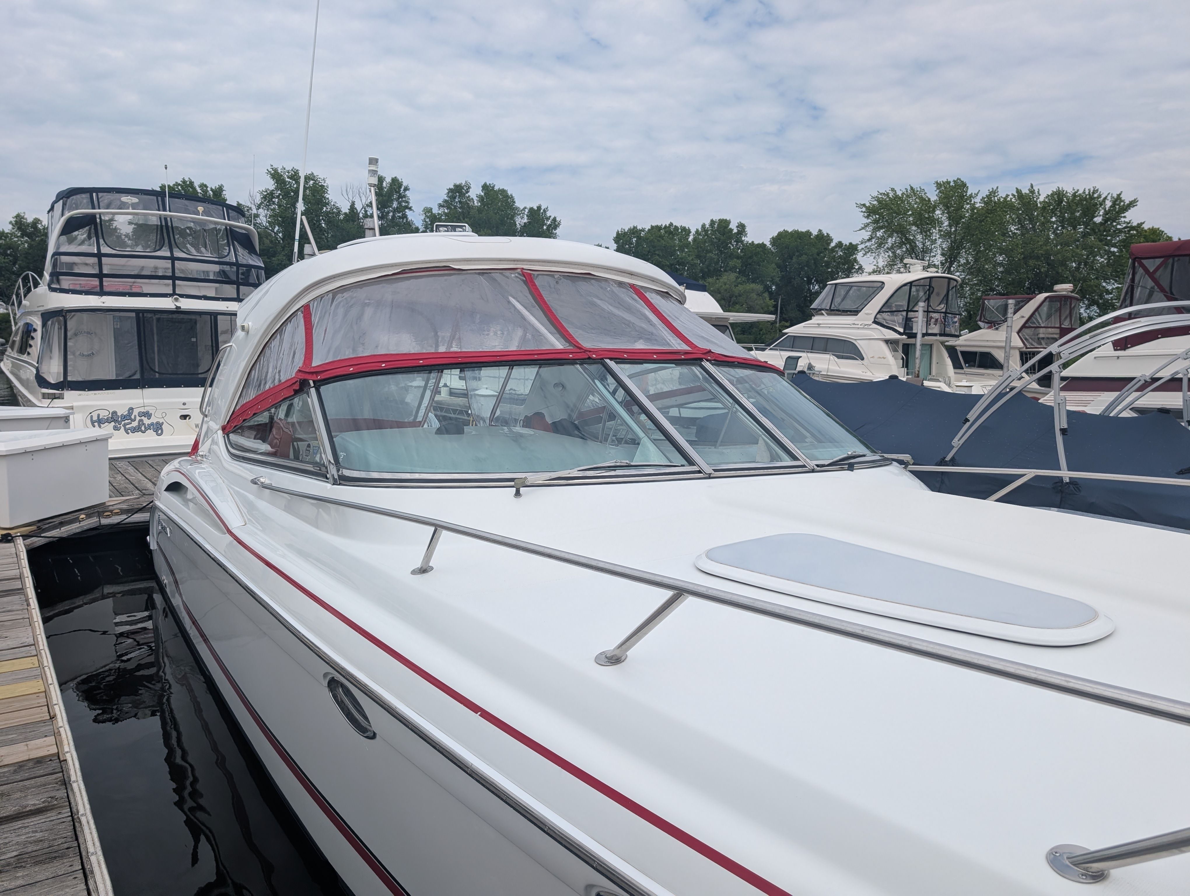 A white motor yacht docked, featuring red accents and an enclosed cockpit.