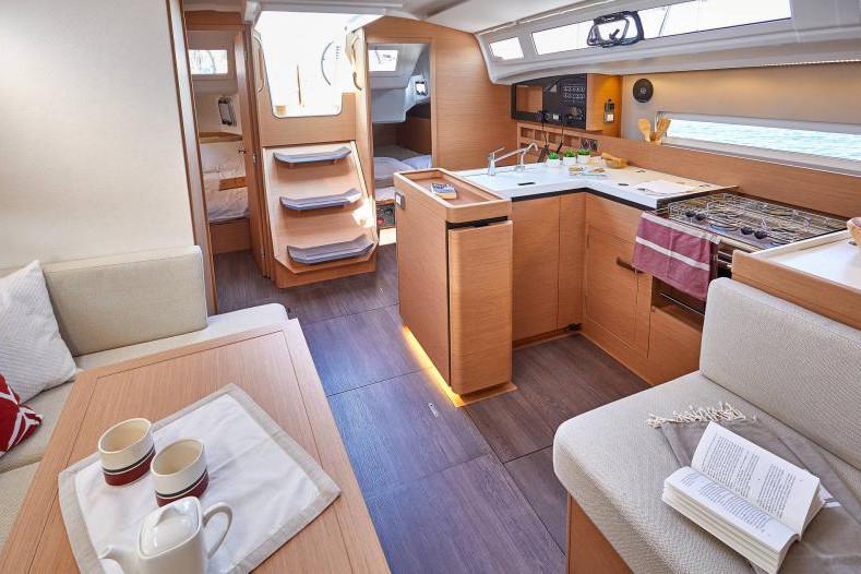 Interior of 2024 Jeanneau Sun Odyssey 410 yacht, featuring modern kitchen and cozy seating area.