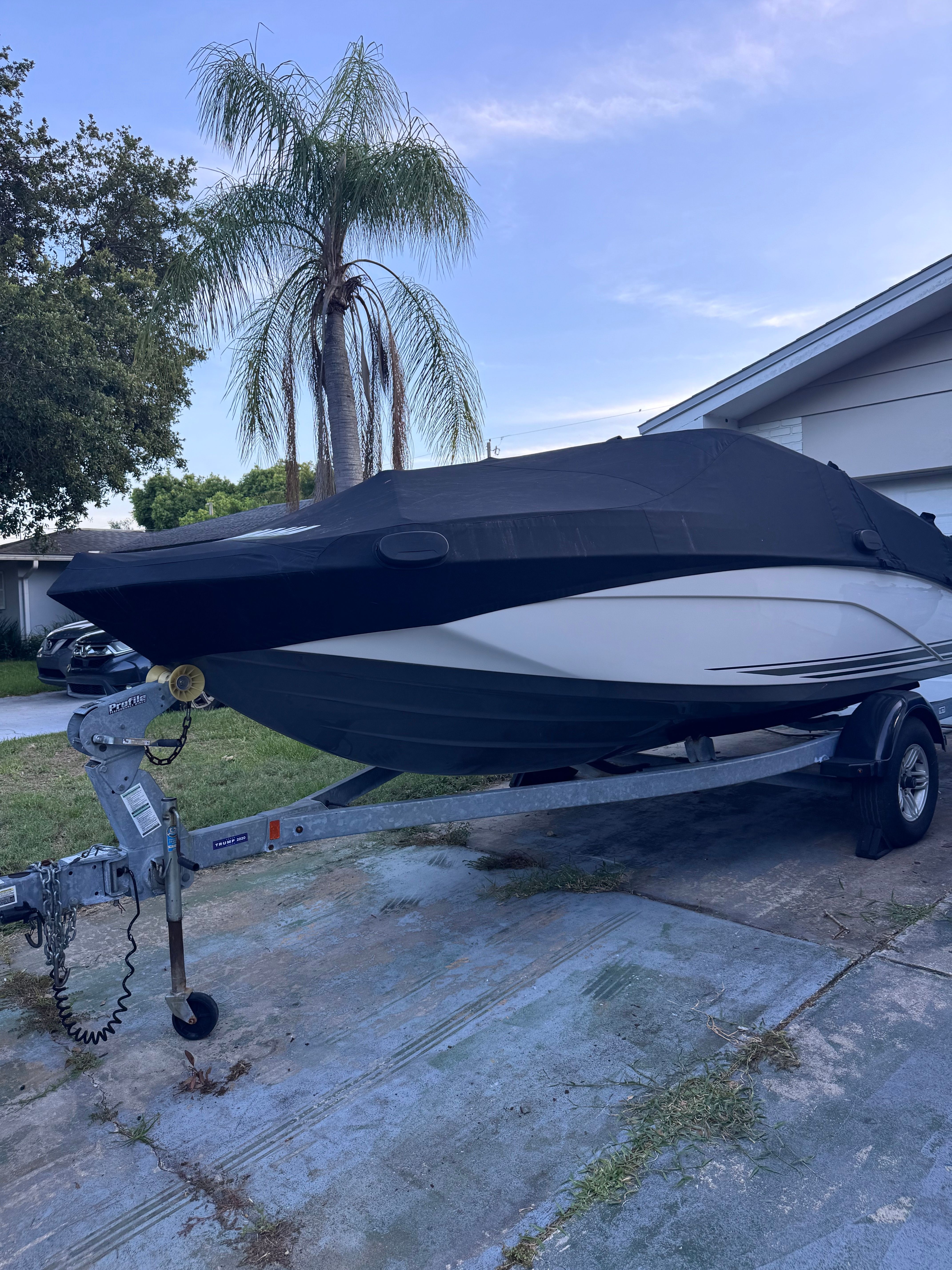 2020 Yamaha SX190 boat on trailer, covered, next to palm trees.