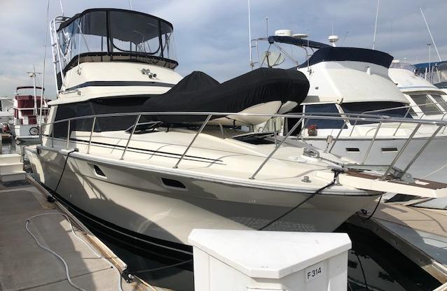 1984 Silverton 34 Convertible yacht docked at marina.
