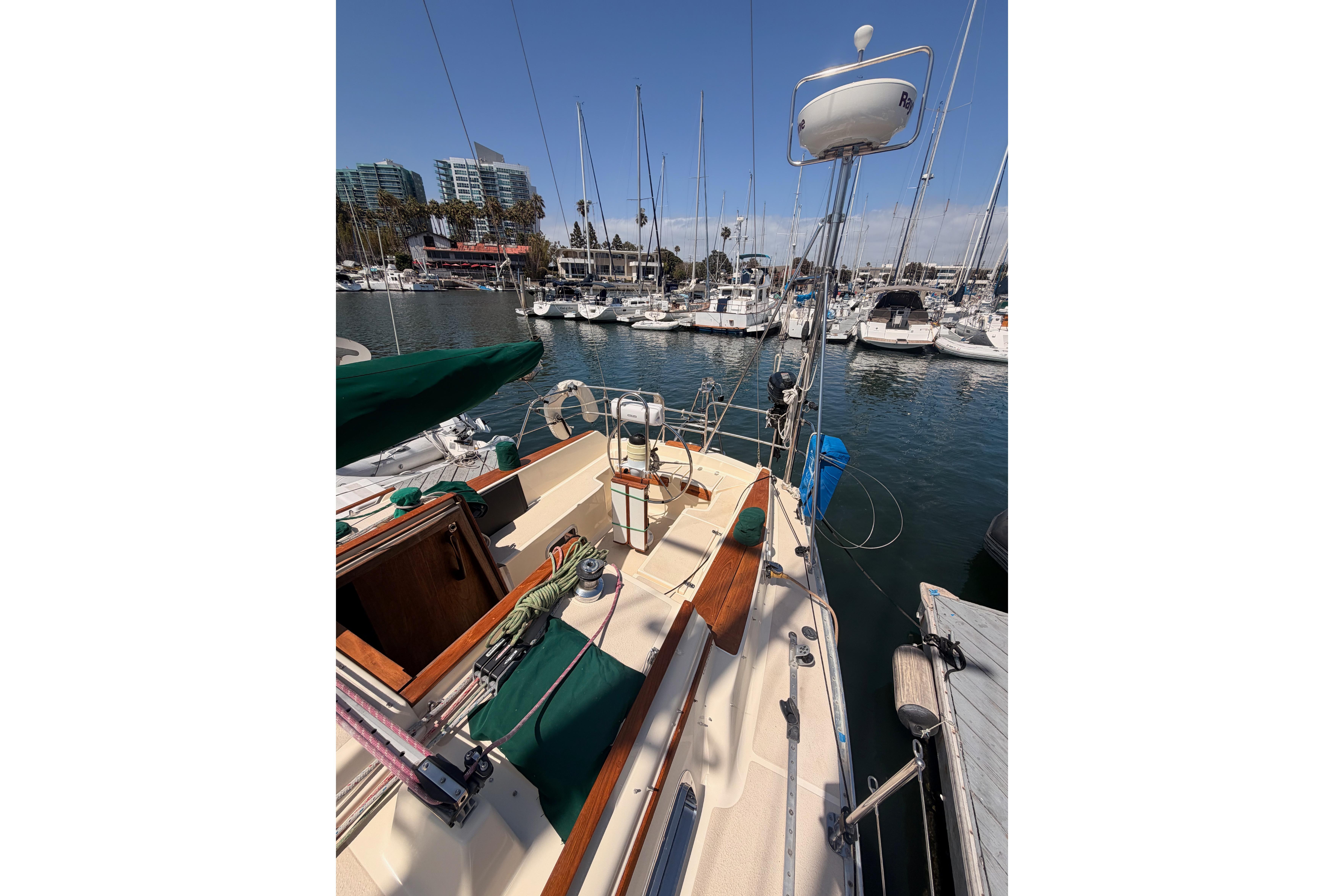 Sailboat docked in marina, Caliber 33 model, 1991, with clear blue sky and surrounding boats.