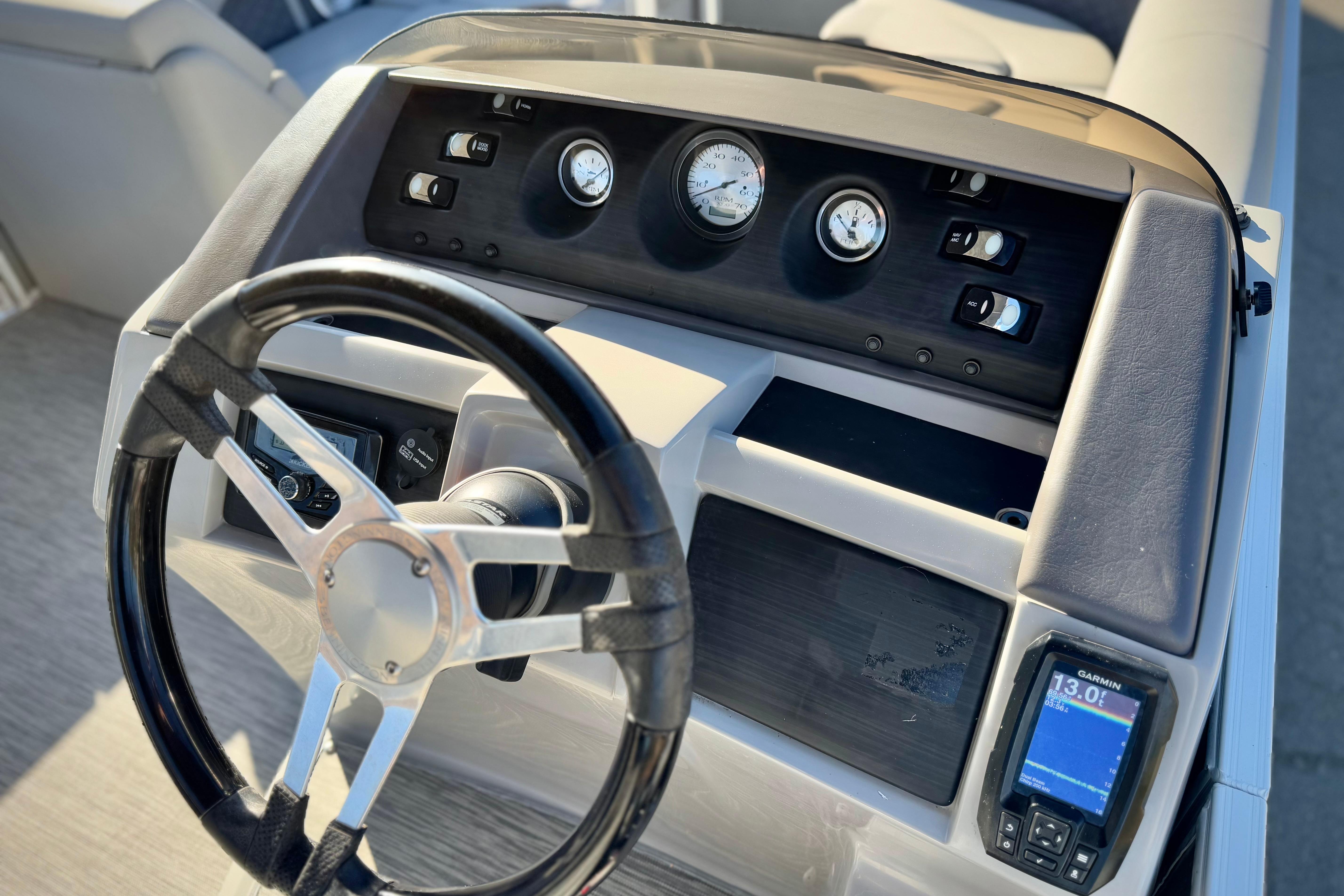 Steering console of a 2021 Bennington 23LSR boat with gauges and Garmin display.