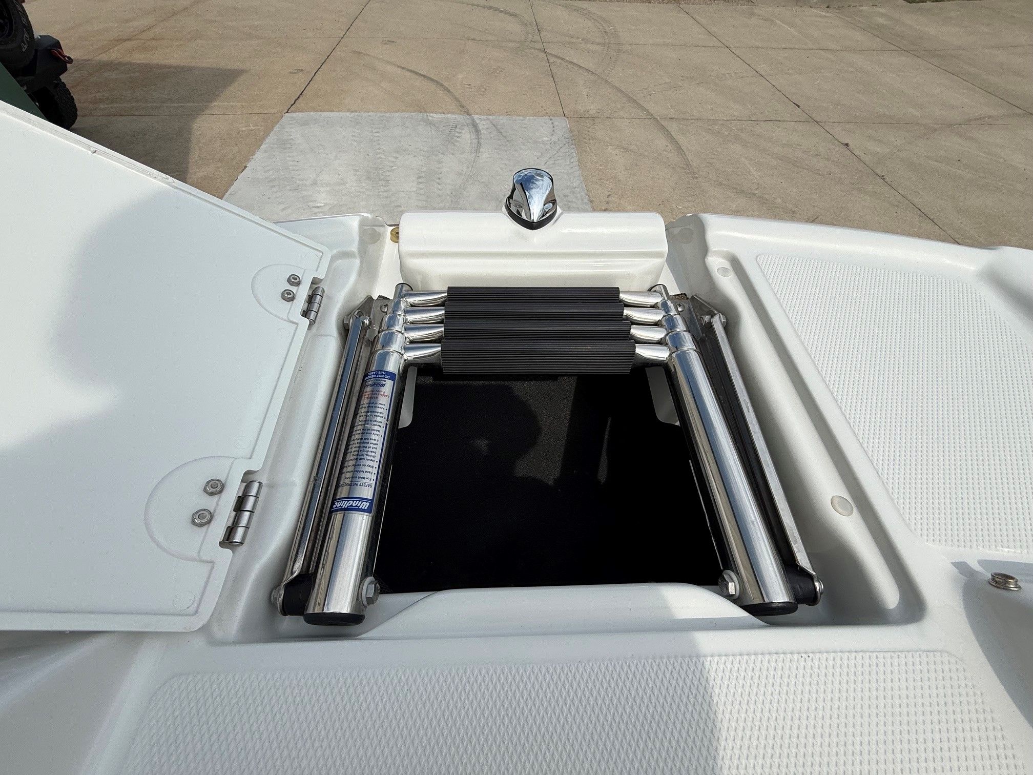 A folded swim ladder on a boat, surrounded by white surfaces.