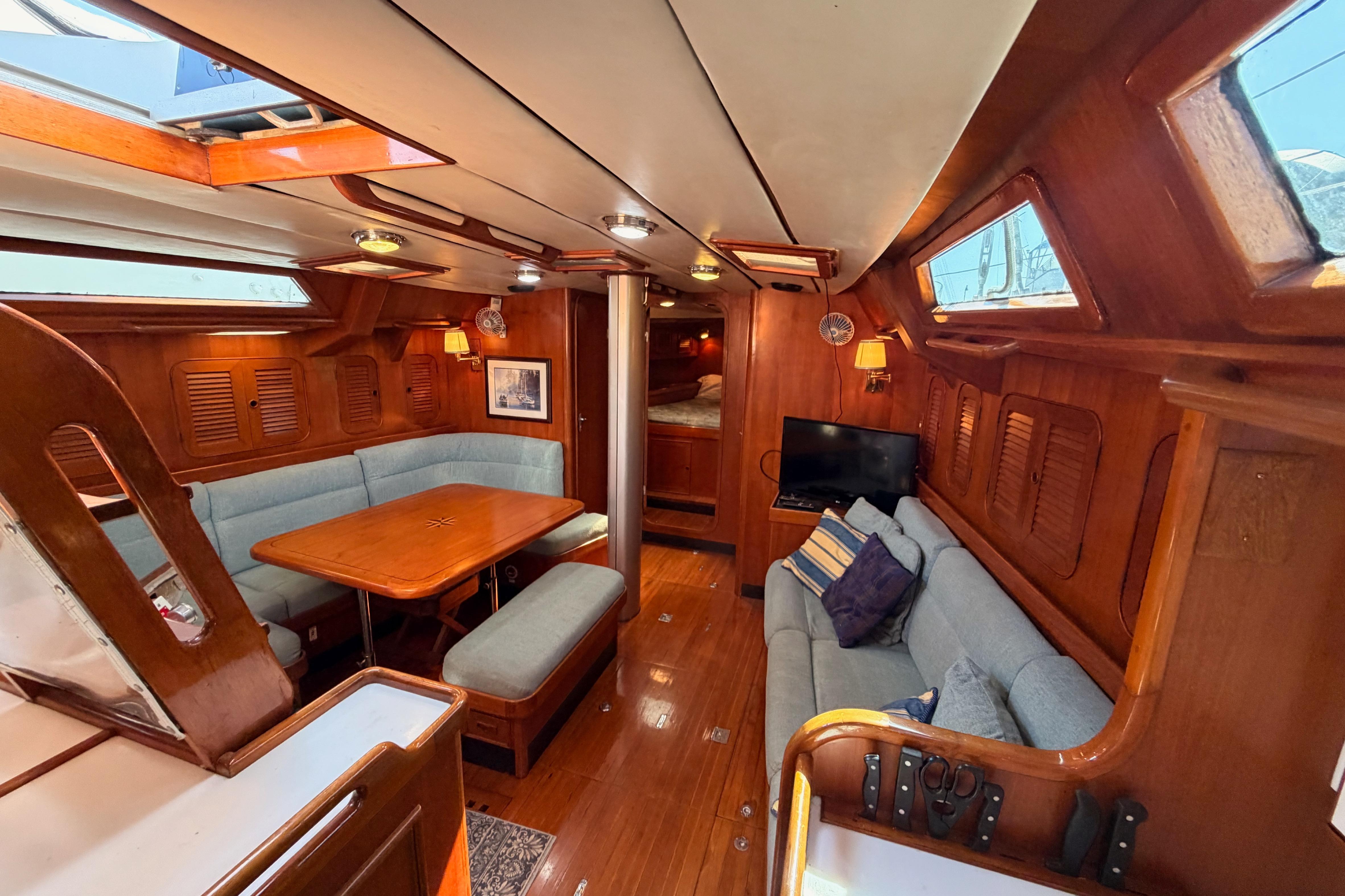 Luxurious 1991 Hylas 51 yacht interior with wooden finishes and cozy seating area.
