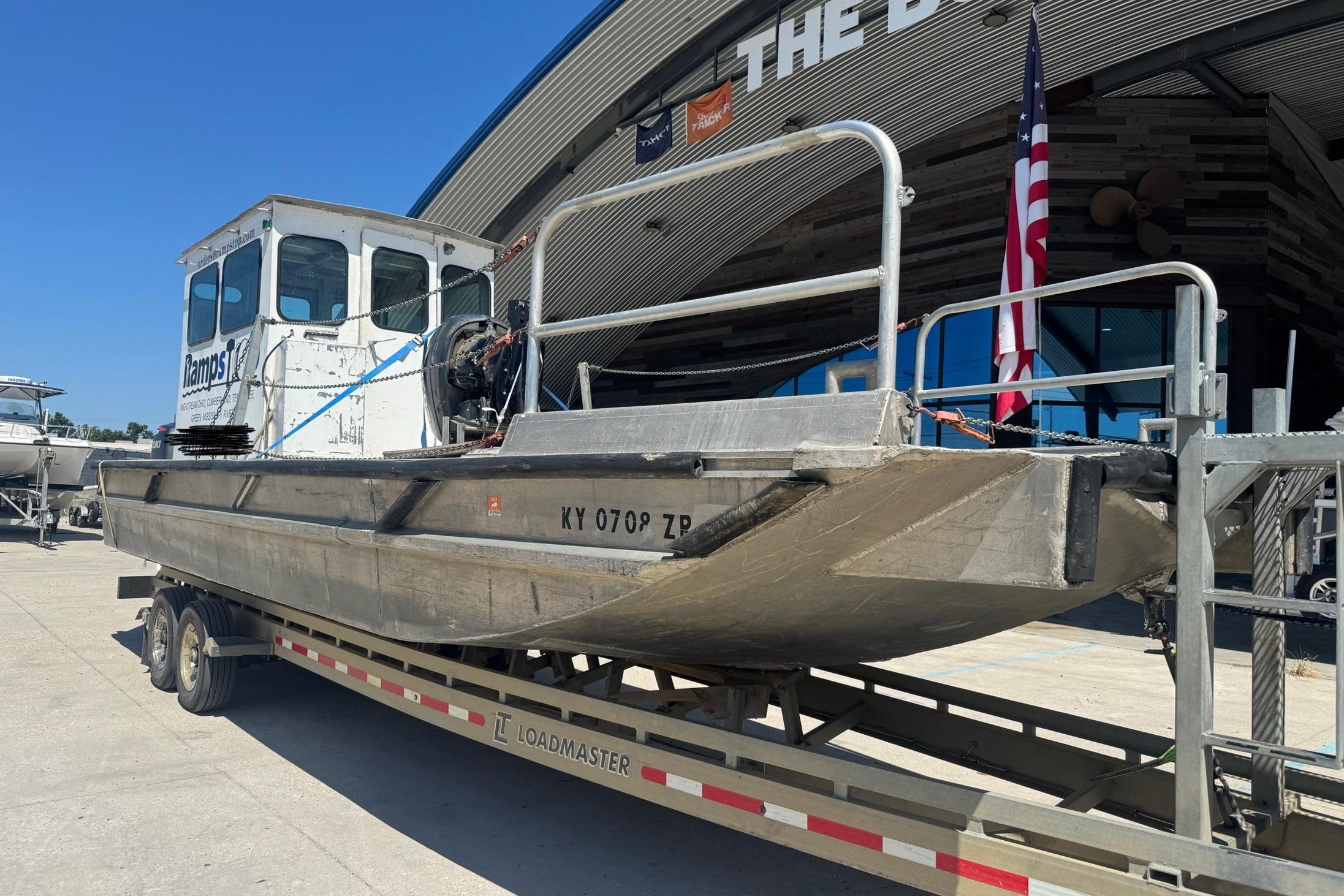 Custom Aluminum Work Boat 33, 2010 model, on trailer outside a building with American flag.