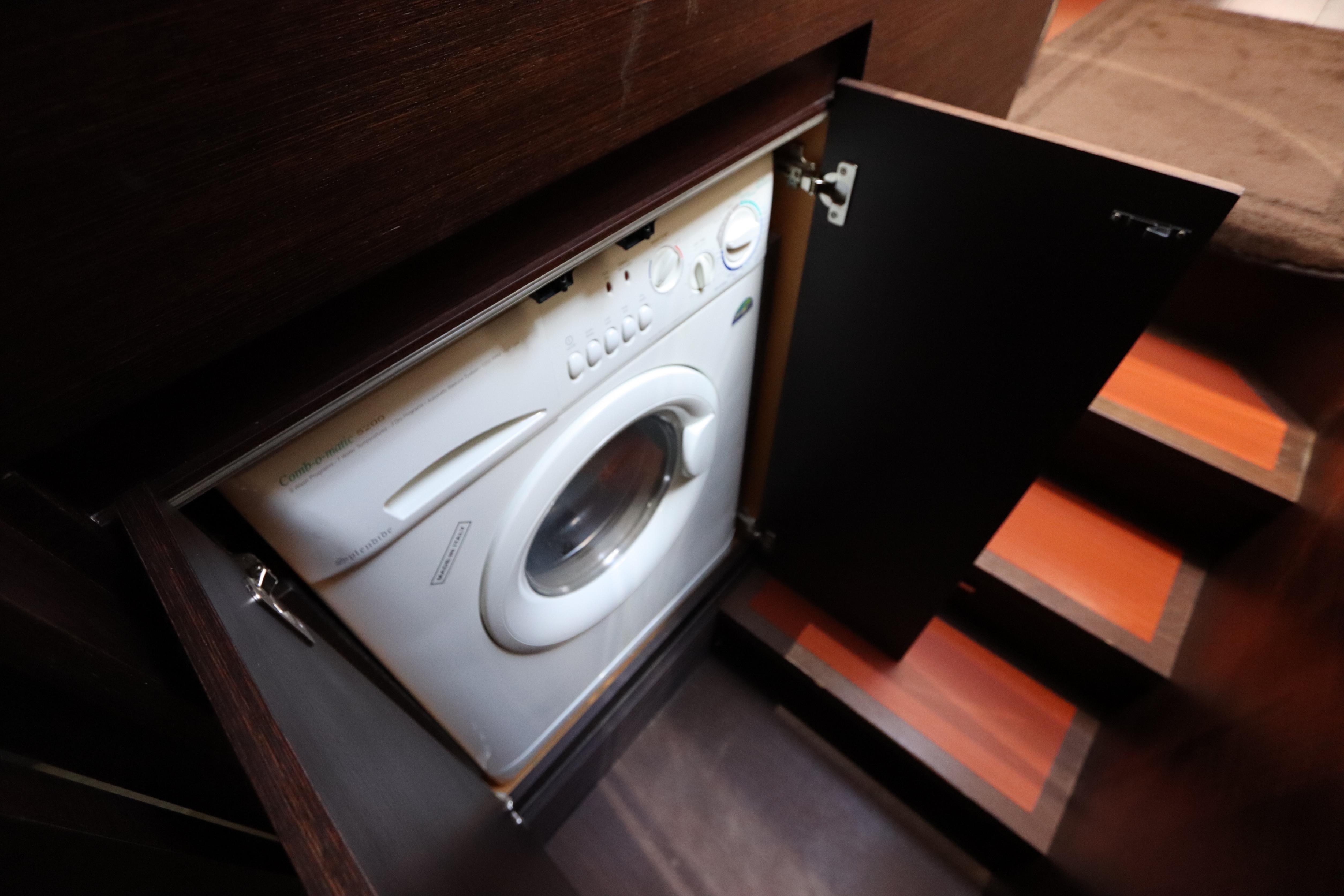 Washing machine in 2007 Azimut 62S yacht, hidden behind wooden cabinet doors.
