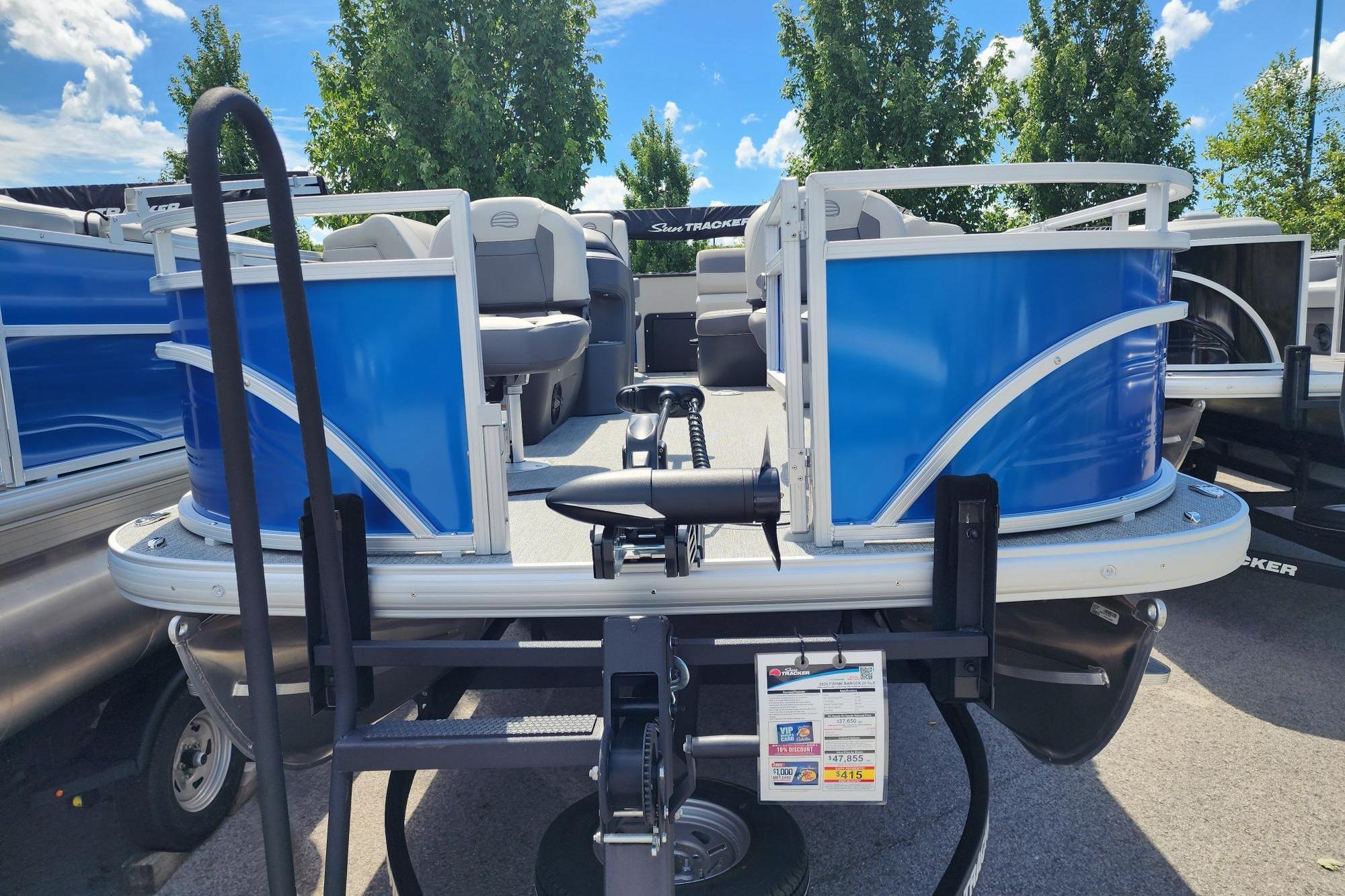 2026 Sun Tracker Fishin' Barge 20 DLX pontoon boat with blue exterior, parked outdoors.