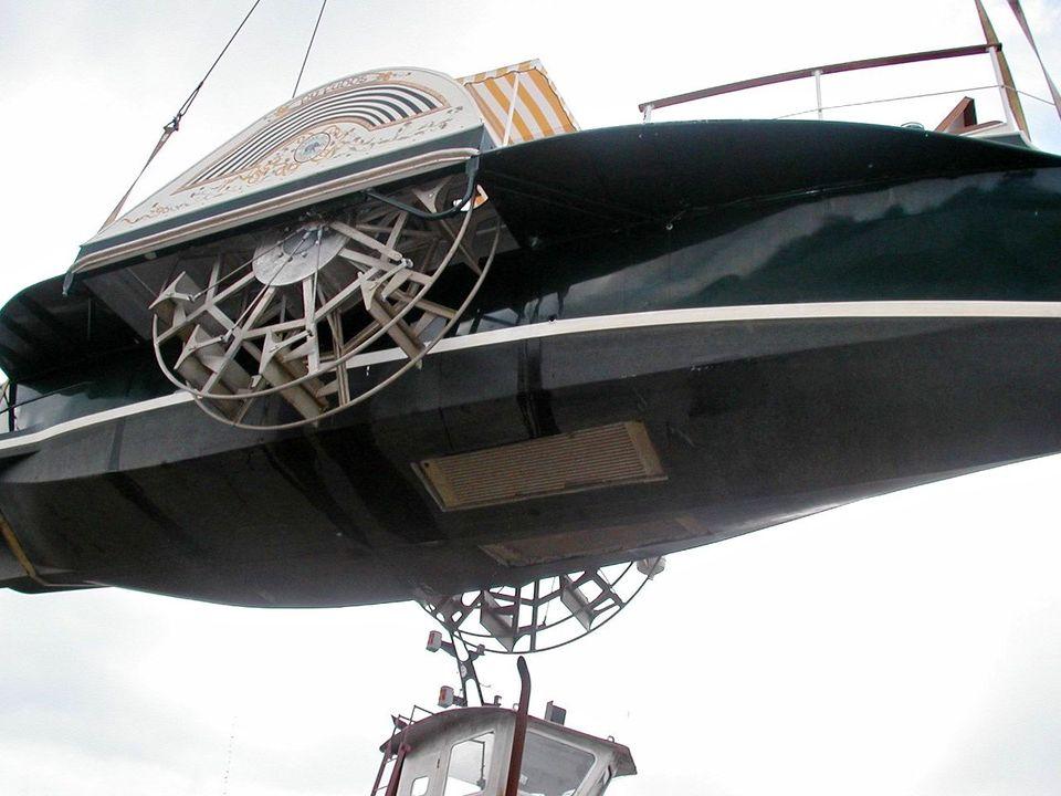 Custom 1987 sidewheel paddle yacht being lifted, showcasing intricate paddle mechanism.