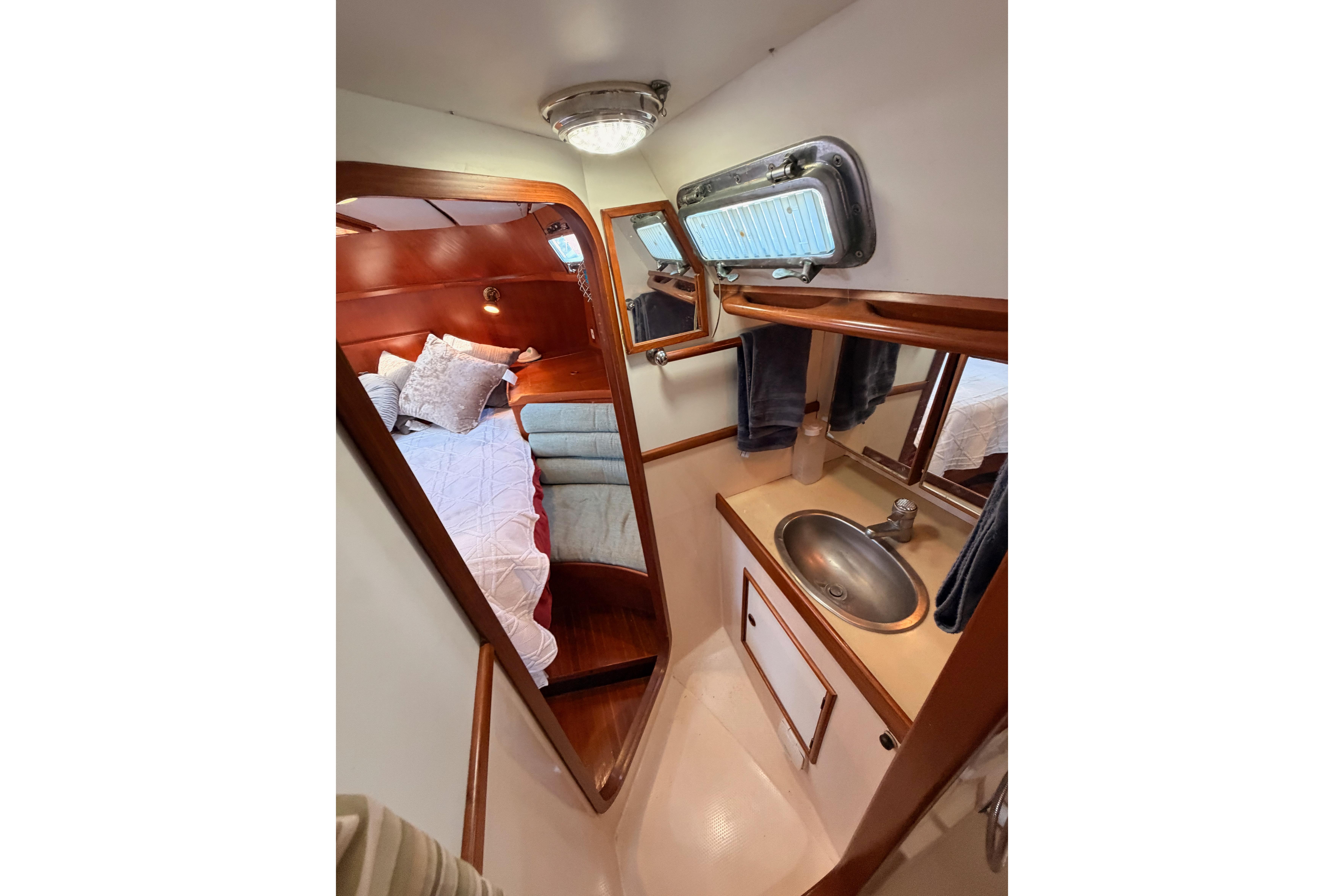 Cozy cabin interior of a 1991 Hylas 51 yacht with bed and sink area.