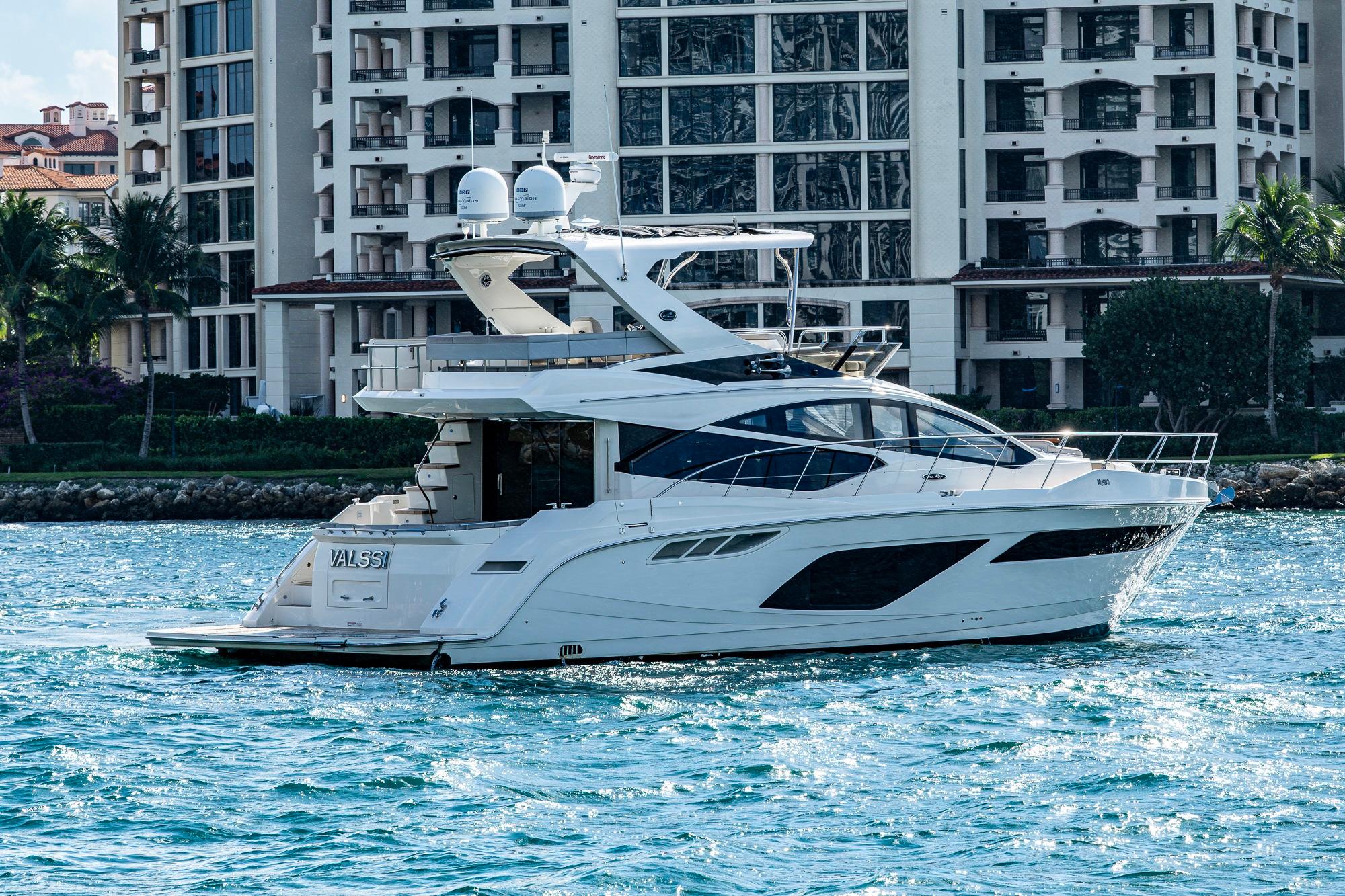 2018 Sea Ray L550 Fly yacht cruising near luxury waterfront buildings.