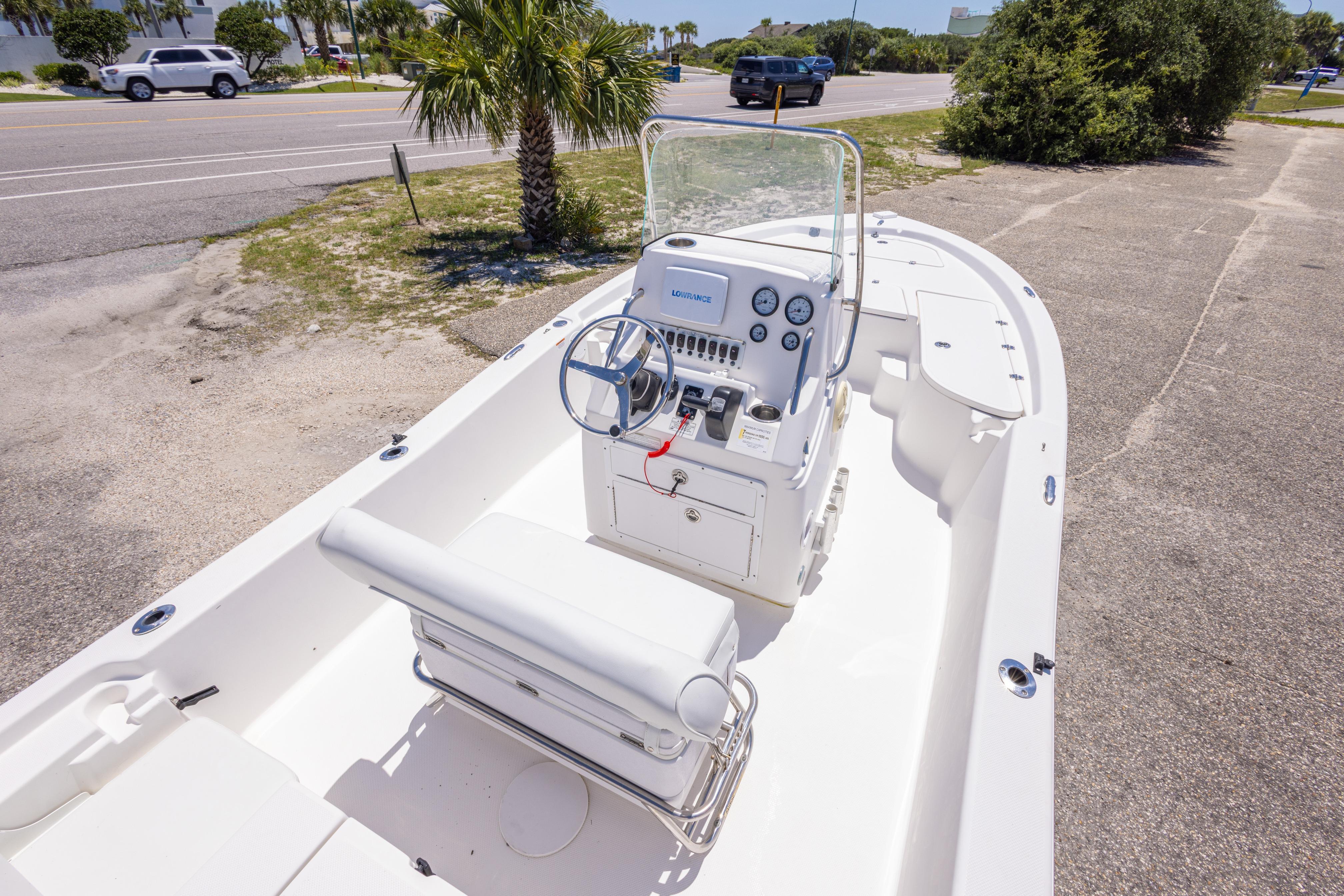 2011 Sea Fox 200XT boat with steering console, parked near a road and palm tree.