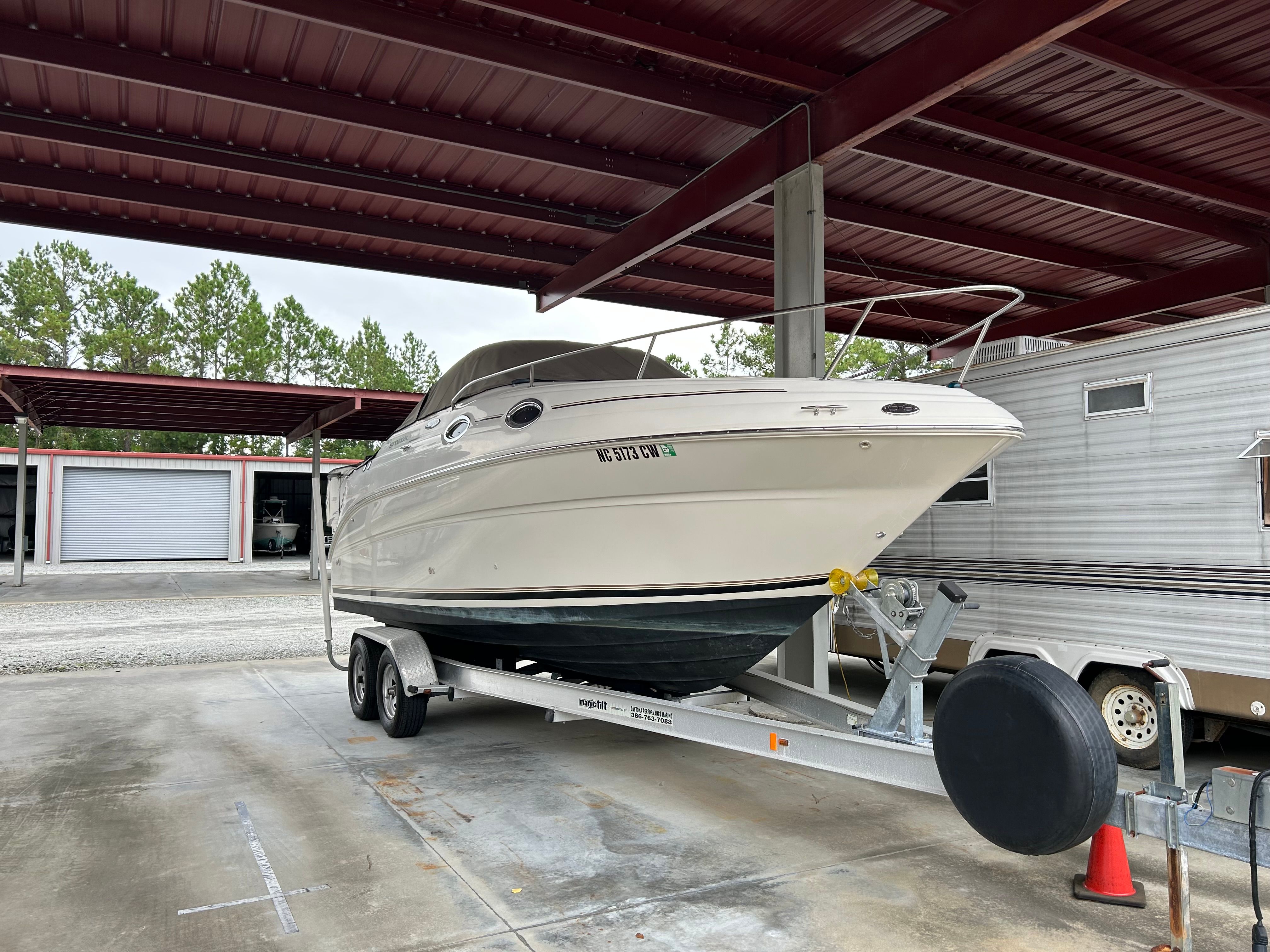 2003 Sea Ray 240 Sundancer boat on trailer under metal canopy.