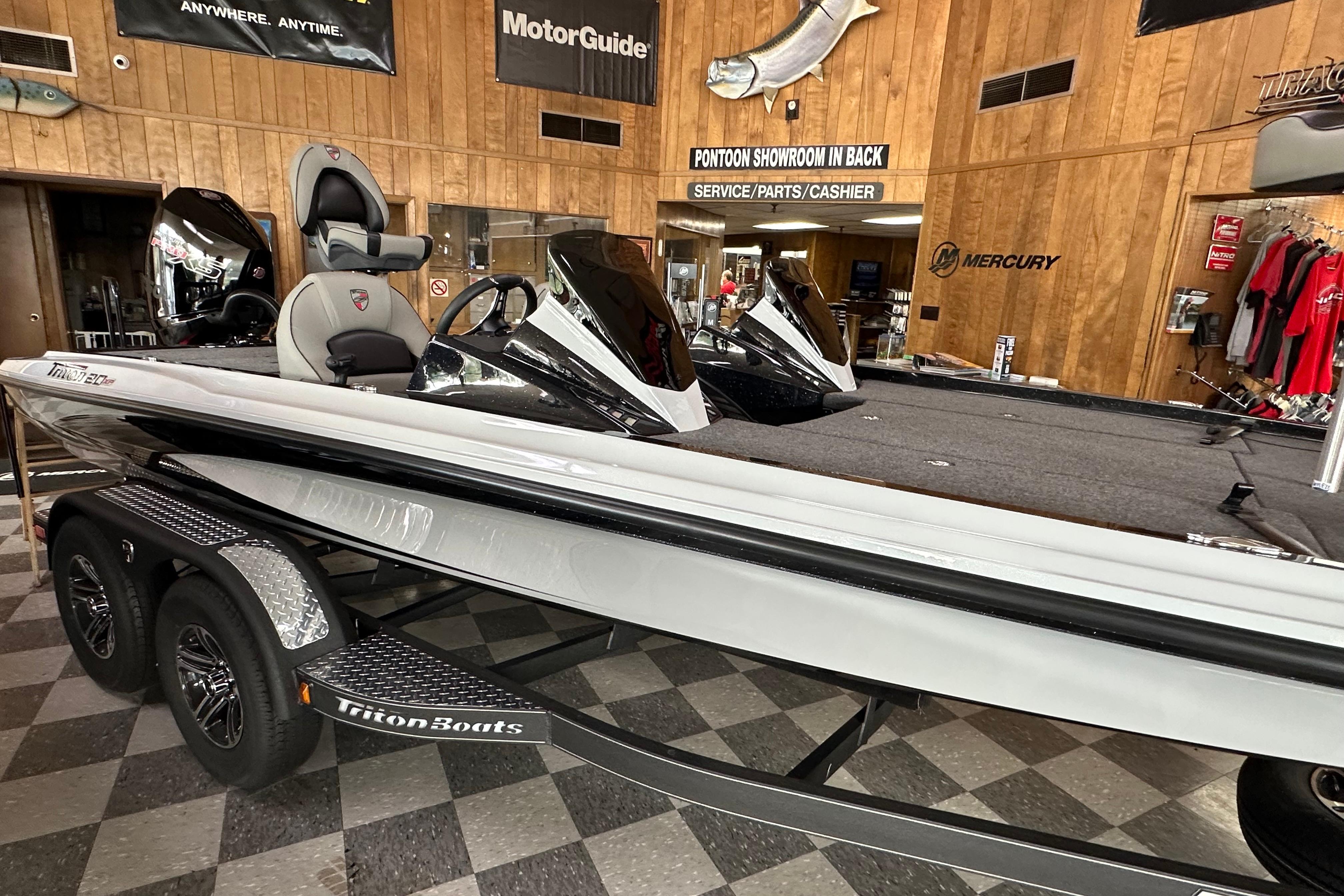 2024 Triton 20XP Patriot boat displayed in showroom with wooden walls and promotional banners.