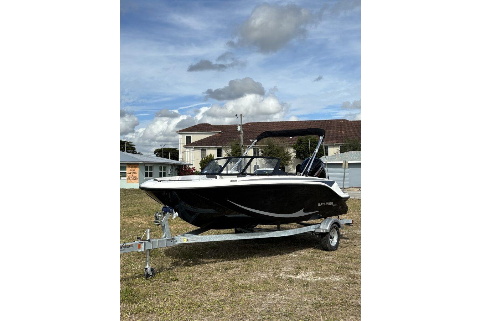 2025 Bayliner Element M17 boat on trailer, parked on grass under cloudy sky.