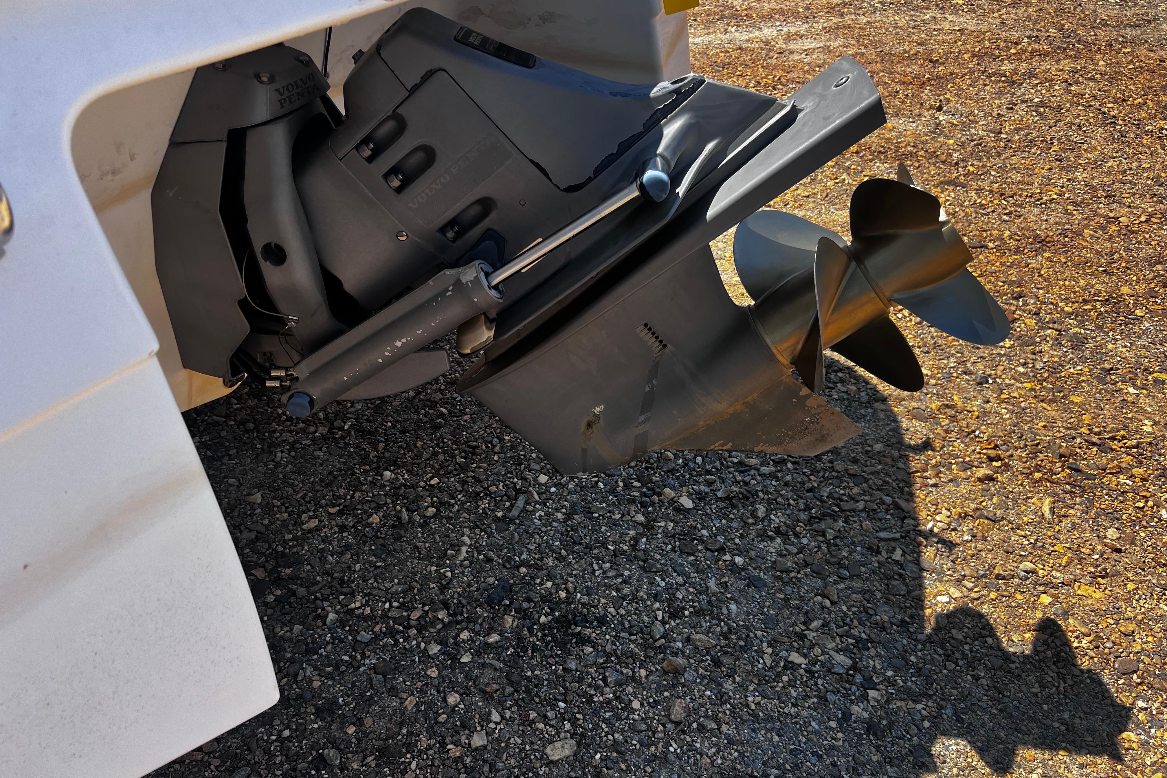 Close-up of a 1998 Four Winns 220 Horizon boat propeller on gravel surface.