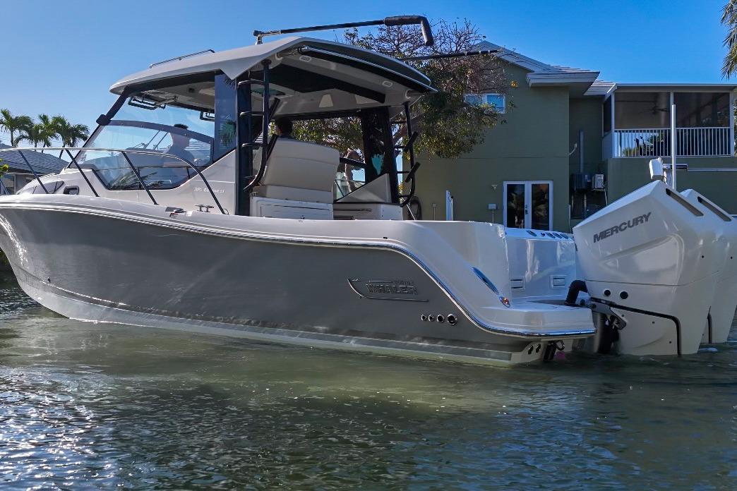 2025 Boston Whaler 325 Conquest boat with Mercury engines on calm water.