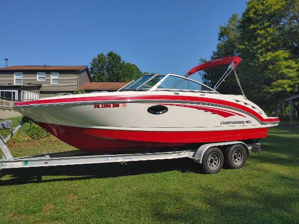 2014 Chaparral 224 Sunesta boat on trailer, red and white, parked on grass.