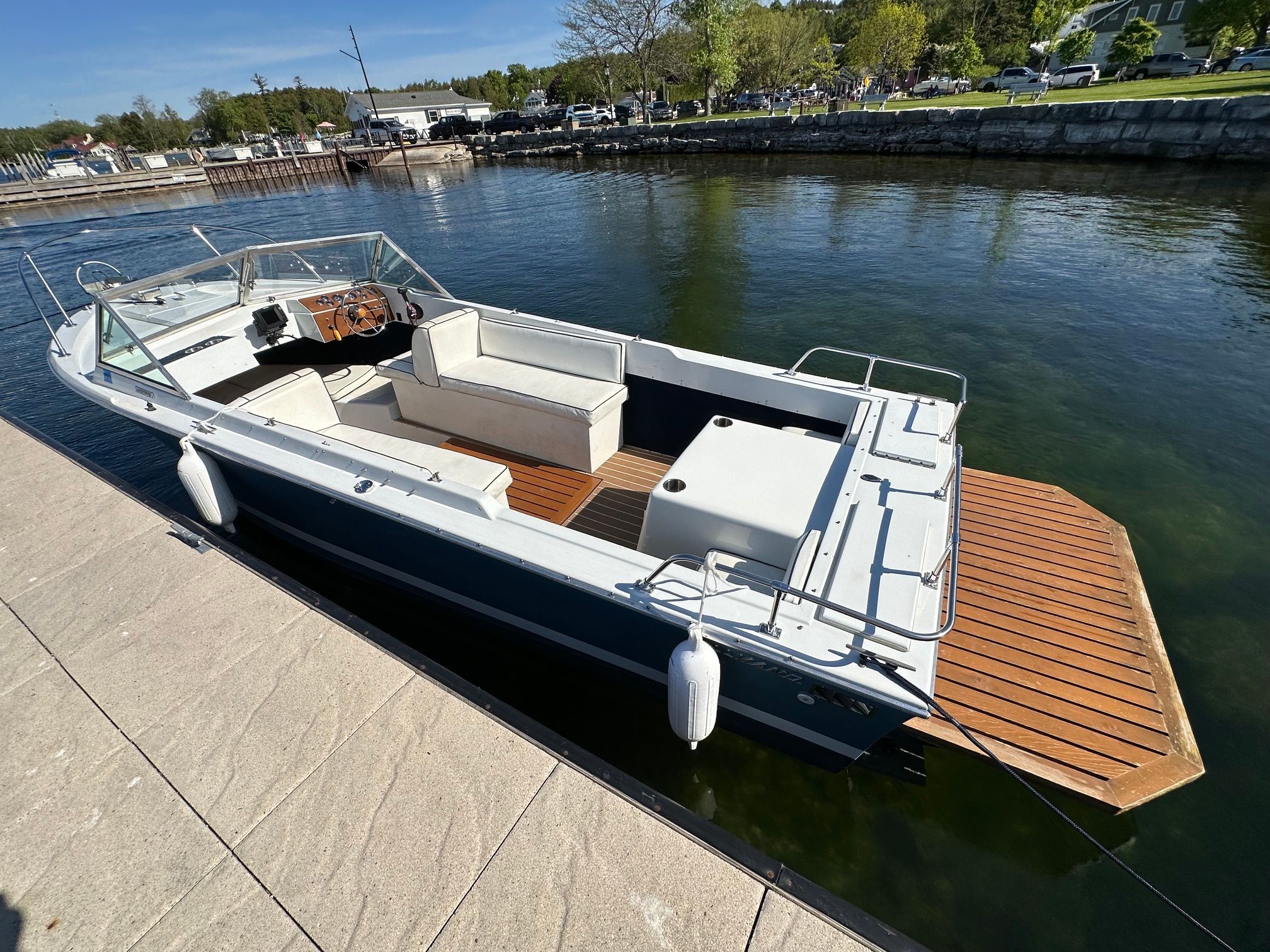 A 1969 John Allmand Citation II docked. It features an open deck and wooden flooring.