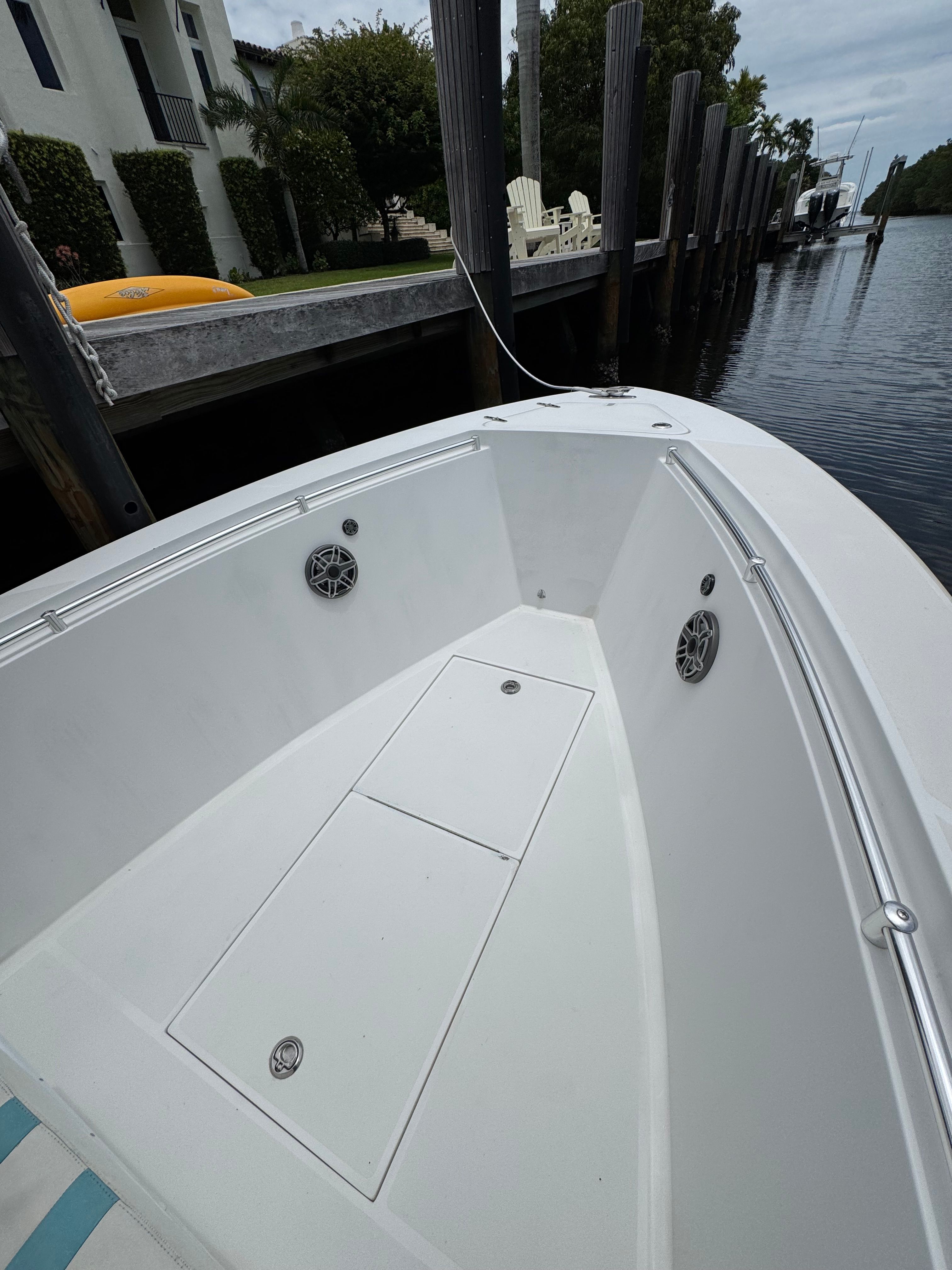 The image shows the bow area of a 2004 Contender 21 boat docked by a pier.