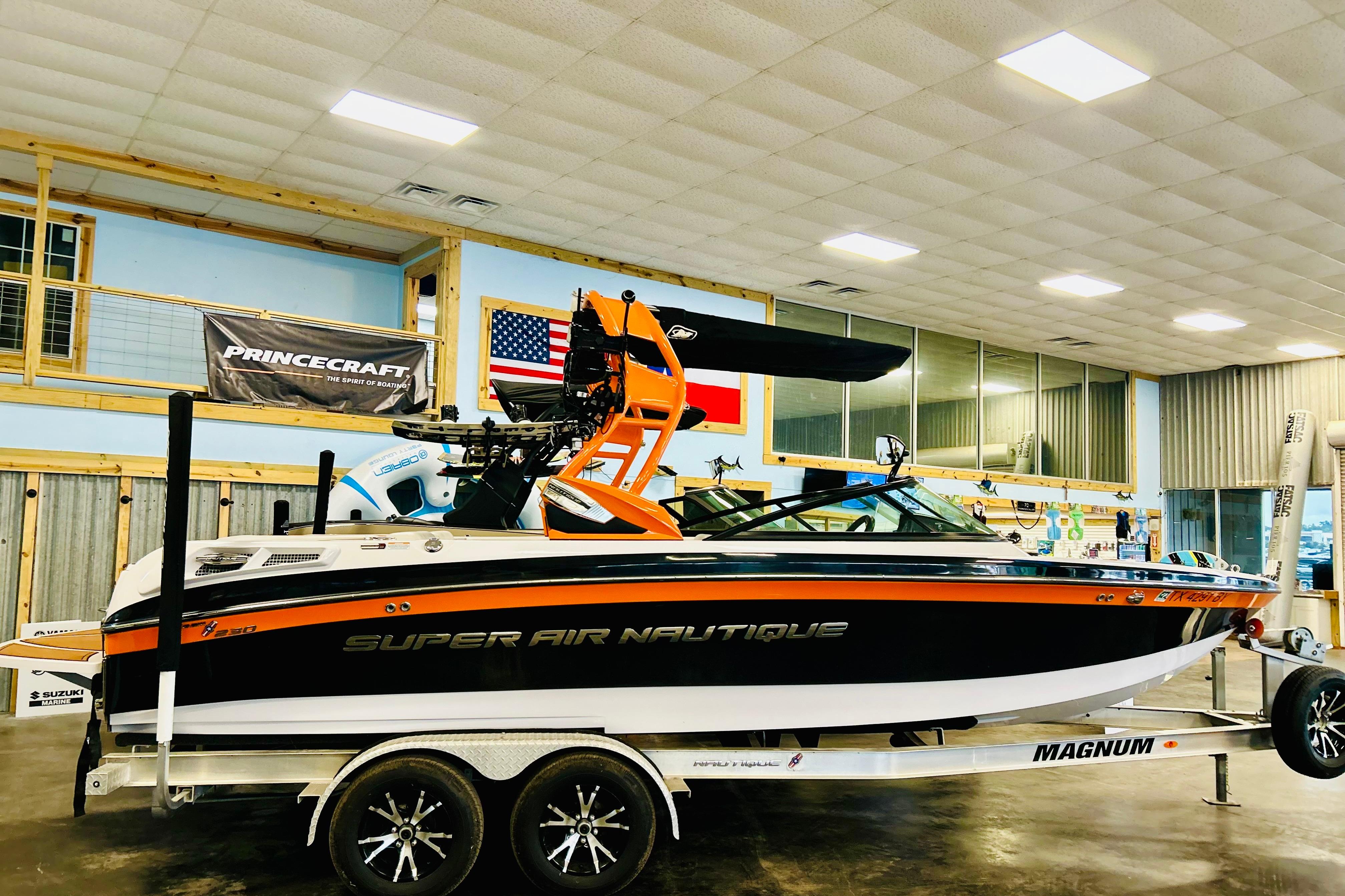 2013 Nautique Super Air Nautique 230 boat on trailer in showroom setting.