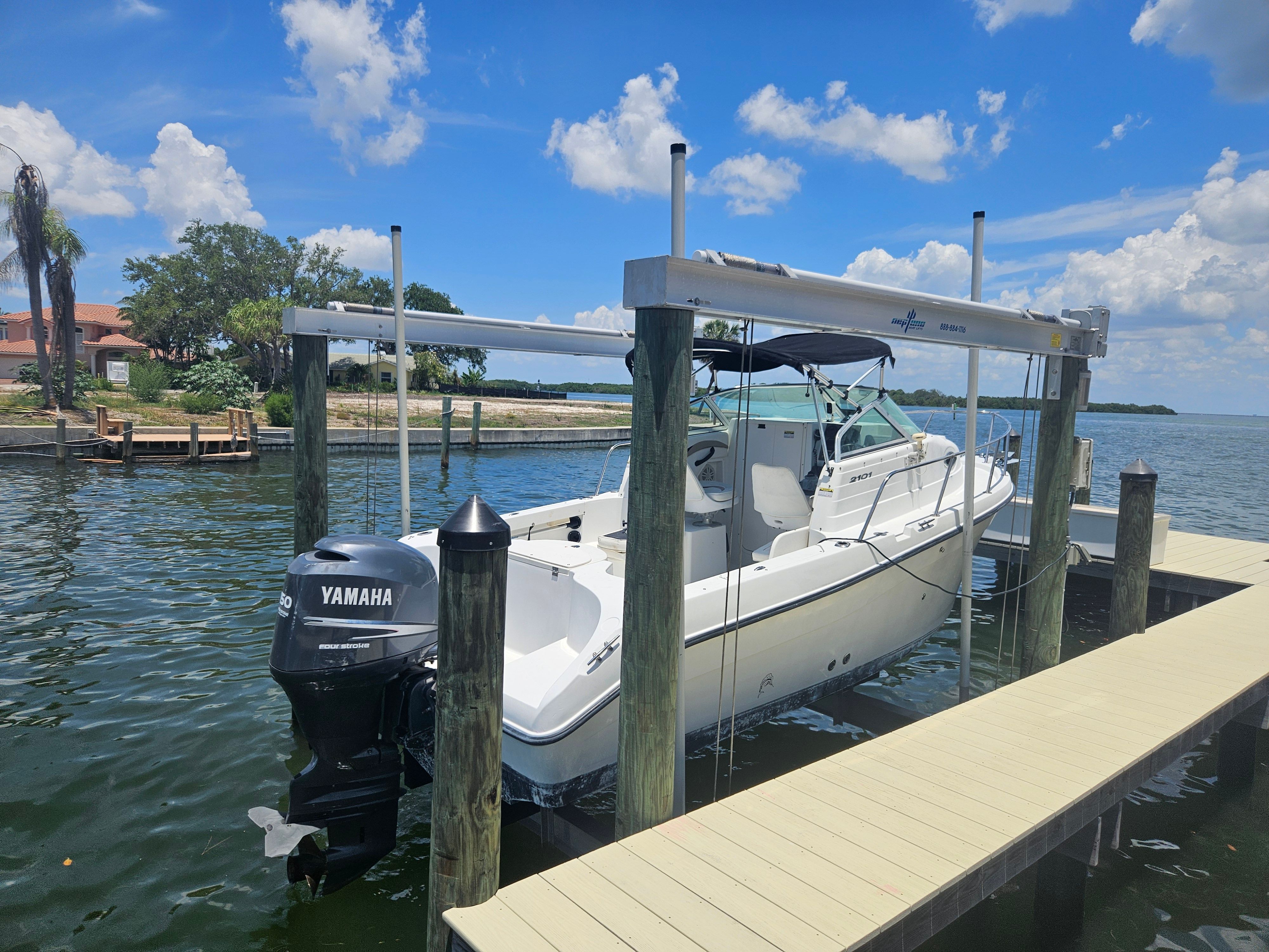 A 2004 Seaswirl Striper 2101 Walkaround O/B on a boat lift by the water.