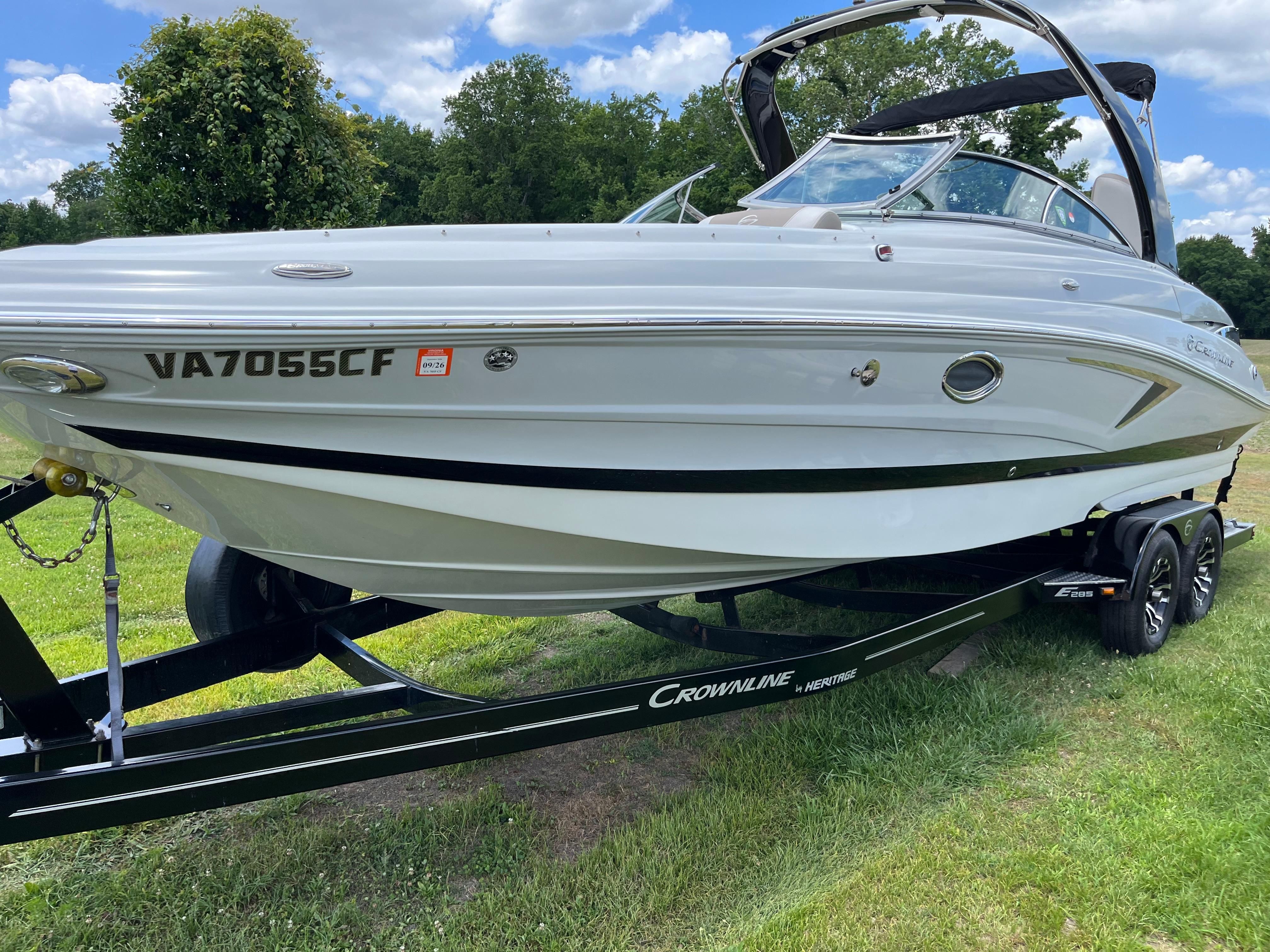 A 2019 Crownline E 285 boat on a trailer, surrounded by grass and trees.