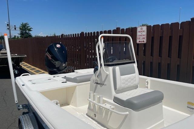 2026 Mako 18 Pro Skiff boat with outboard motor, parked near a wooden fence.