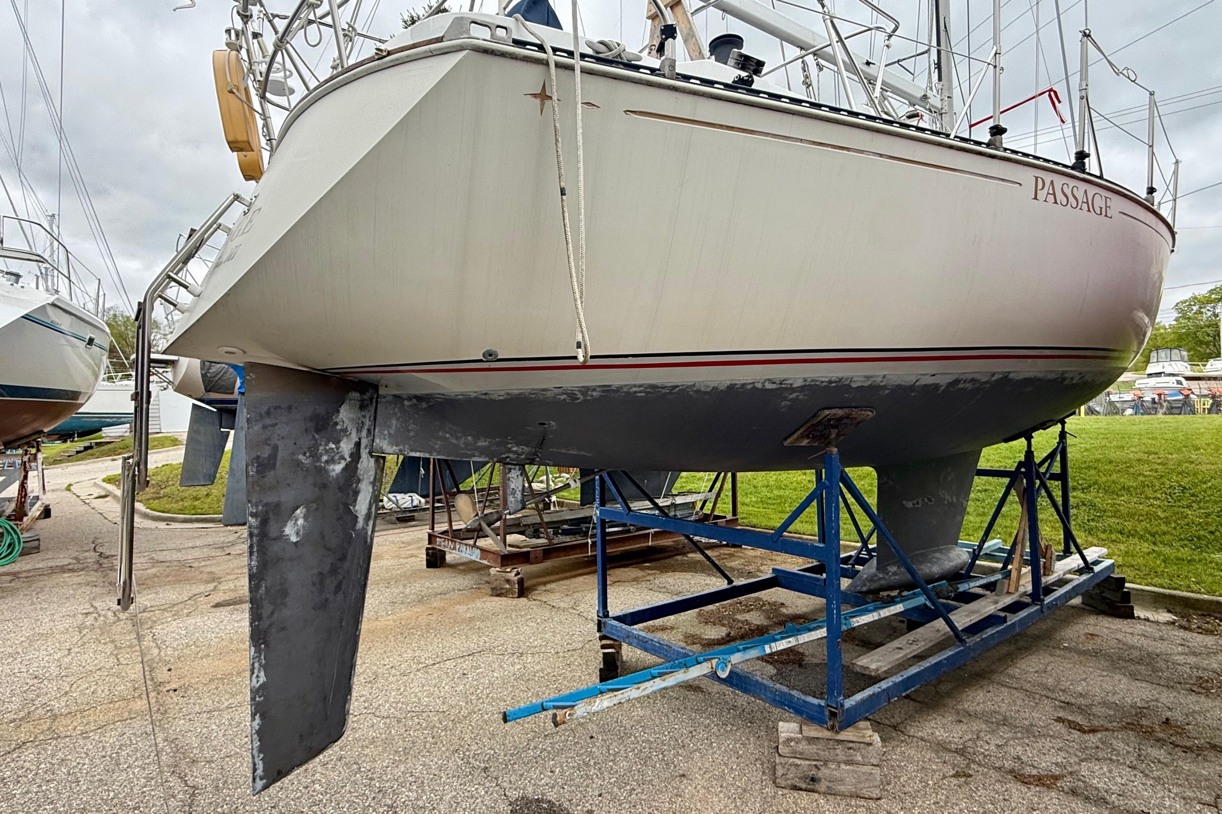 1983 C&C 34 sailboat on a stand, showing hull and keel in a boatyard.