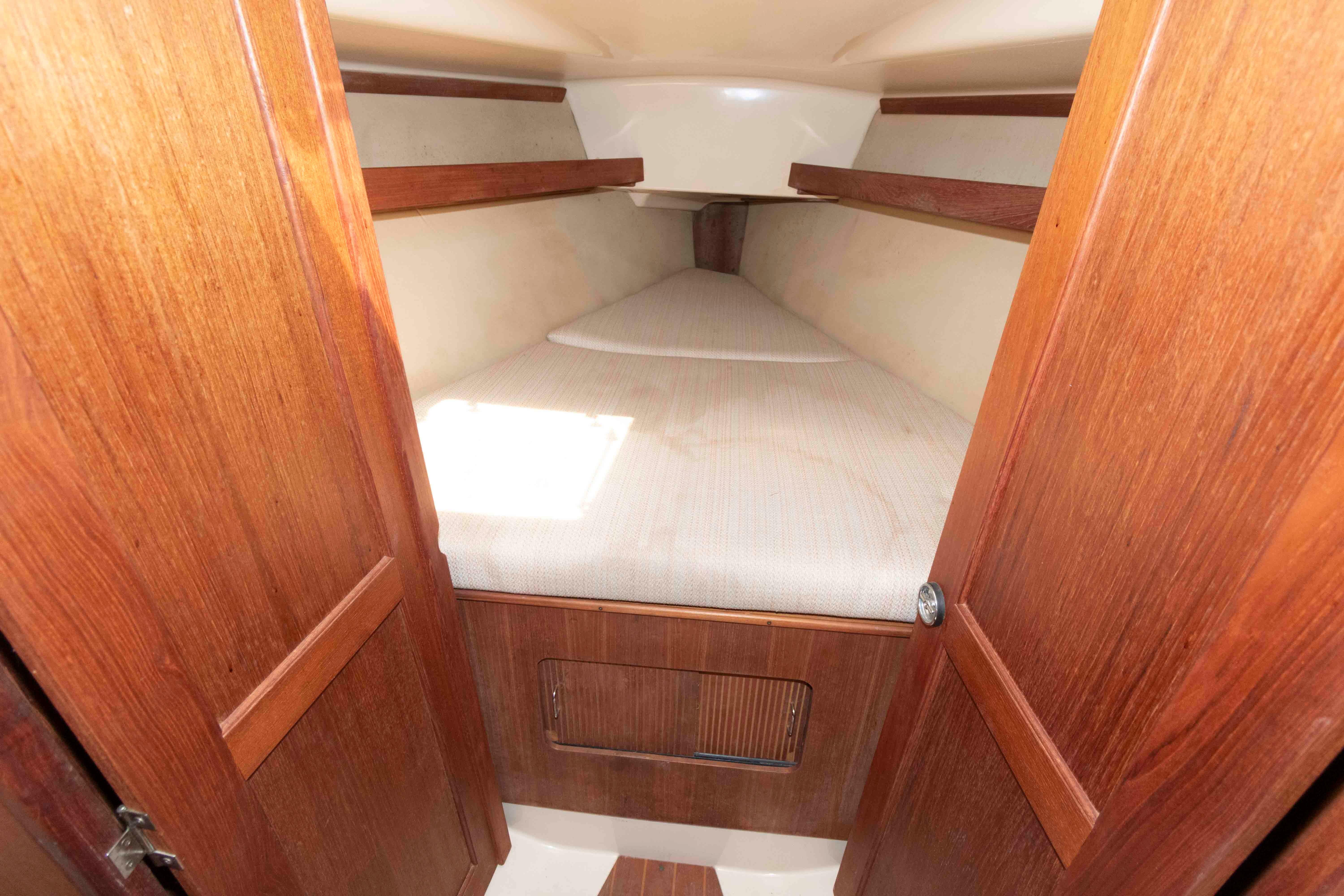 Interior cabin of 1989 Hunter 35.5 sailboat with wooden finish and cozy sleeping area.