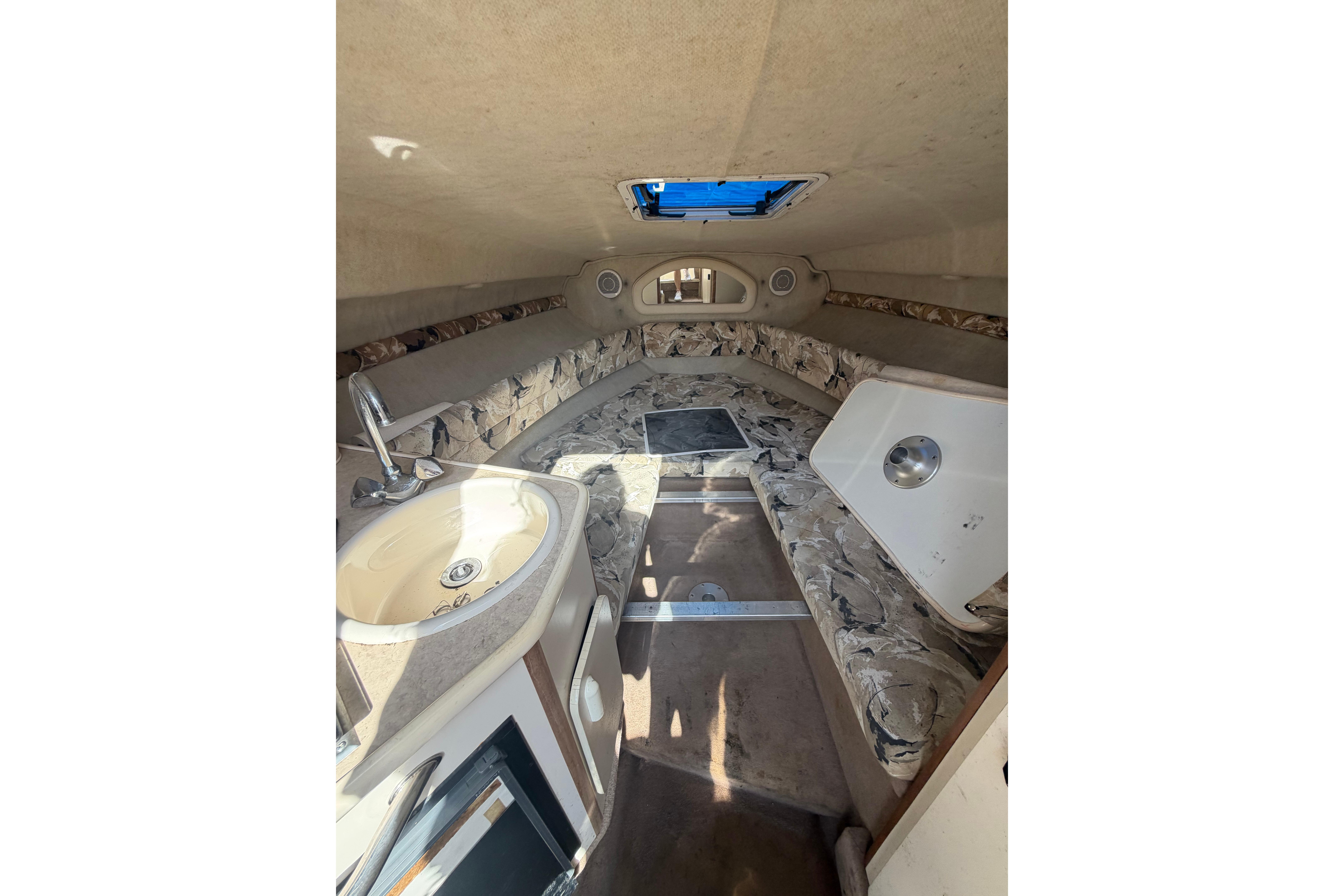 Interior of 1999 Sea Ray 240 Sundancer boat with sink and seating area.