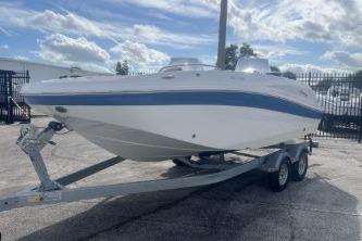 2022 Hurricane SunDeck 192 OB boat on trailer, parked outdoors under a cloudy sky.