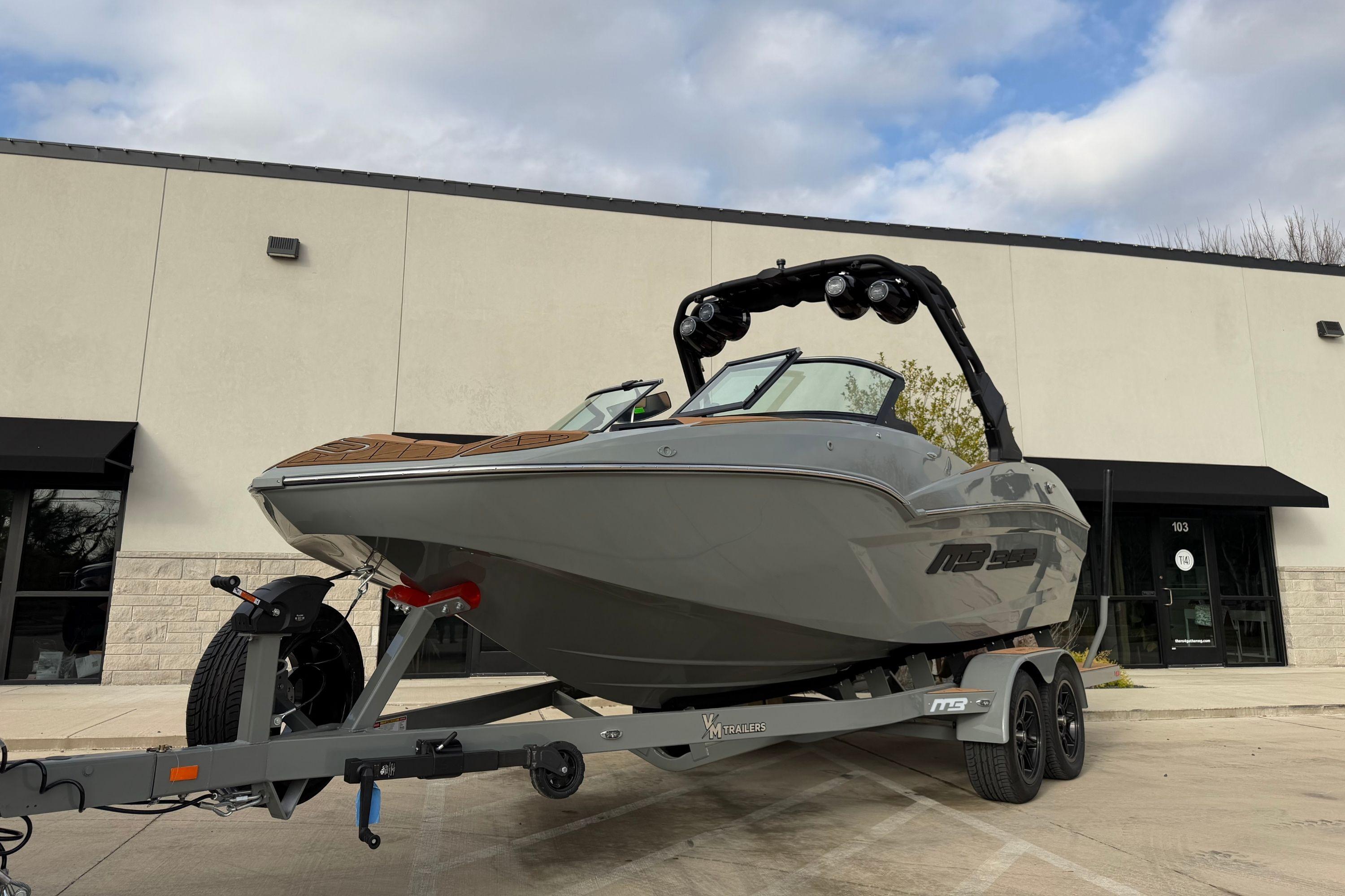 2026 MB B52 21 Alpha boat on trailer outside building under cloudy sky.