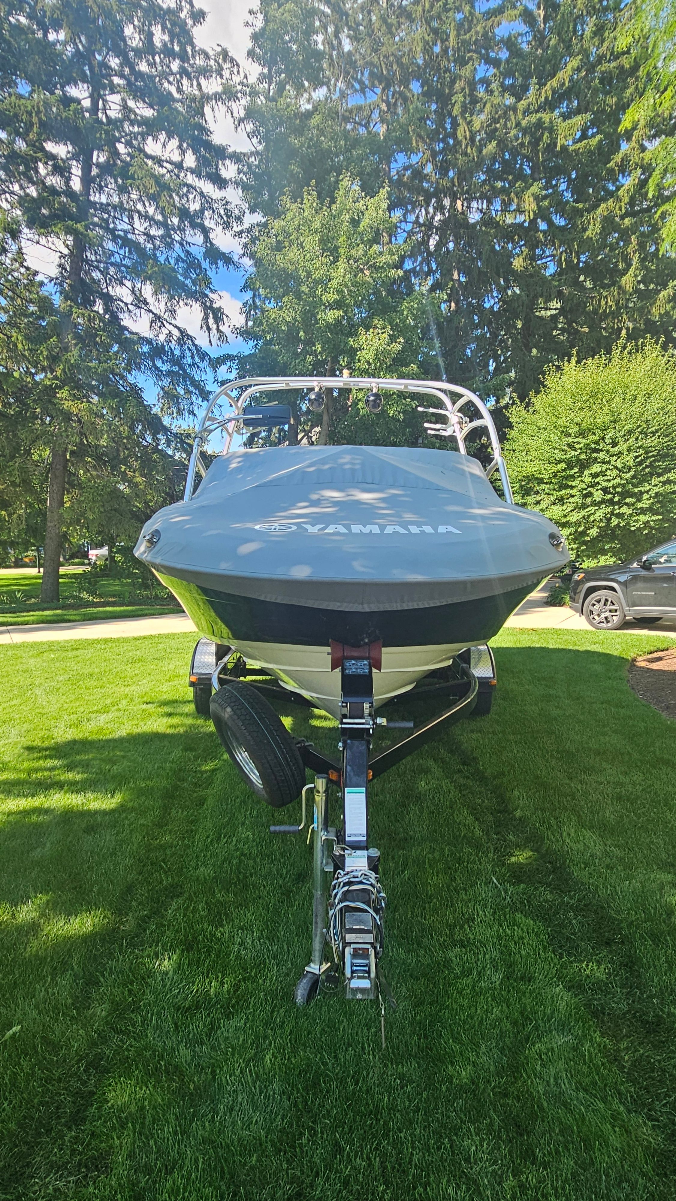 A 2010 Yamaha AR210 boat on a trailer, set on a grassy lawn.
