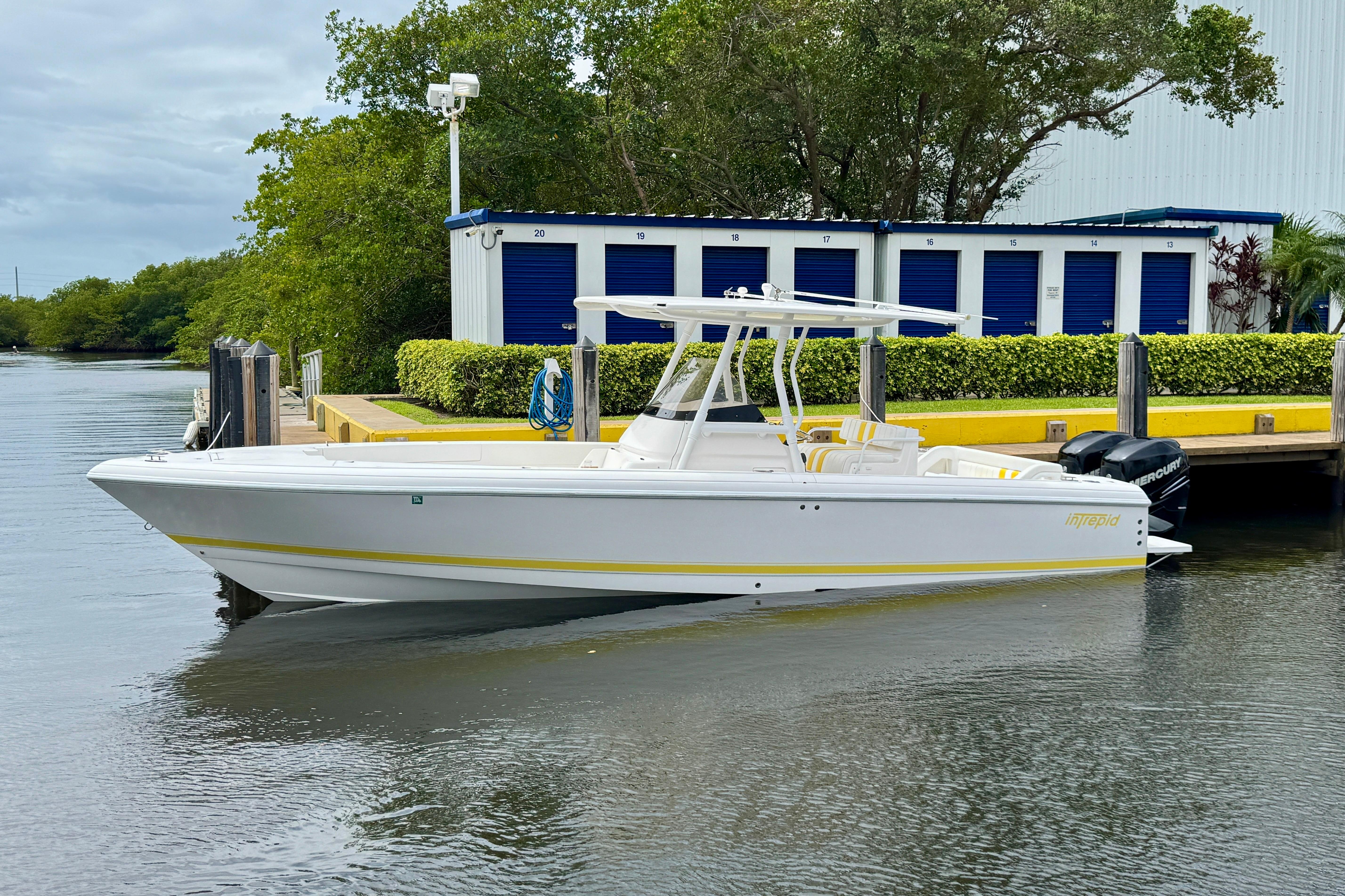 2013 Intrepid 300 Center Console boat docked near storage units.