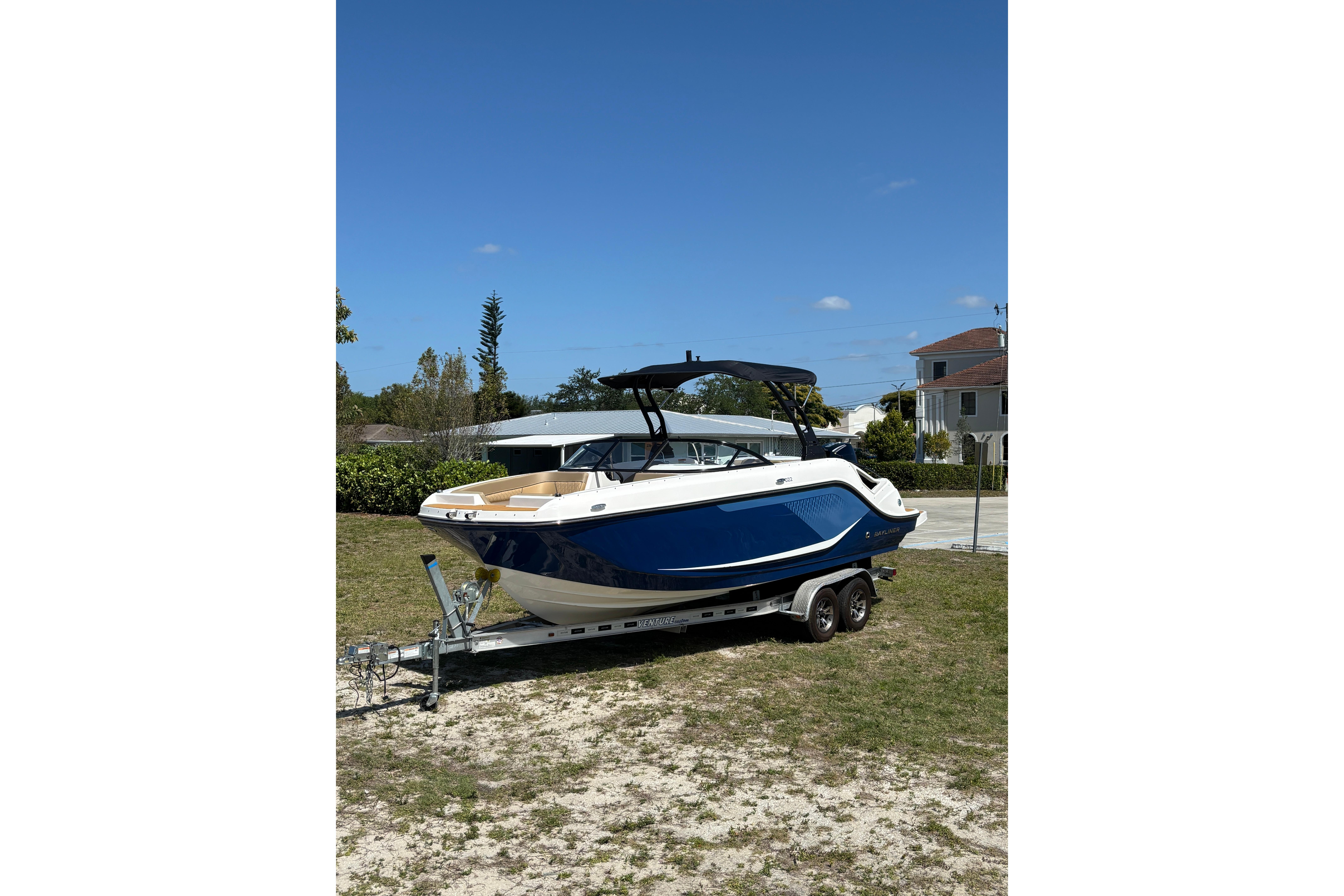 2026 Bayliner D22 boat on trailer, parked outdoors under clear blue sky.