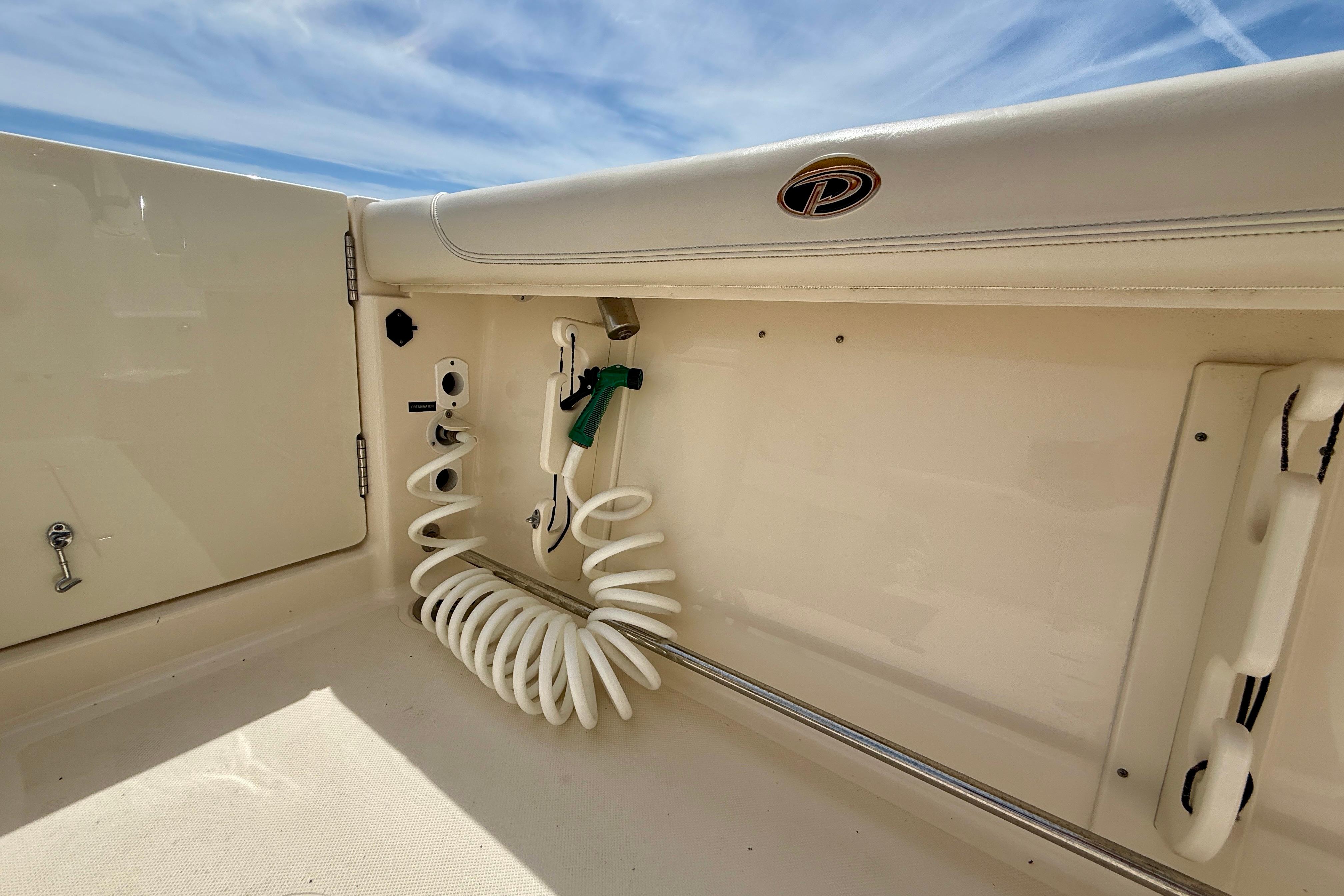 Interior view of a 2012 Pursuit OS 345 Offshore boat, featuring a coiled hose and storage area.