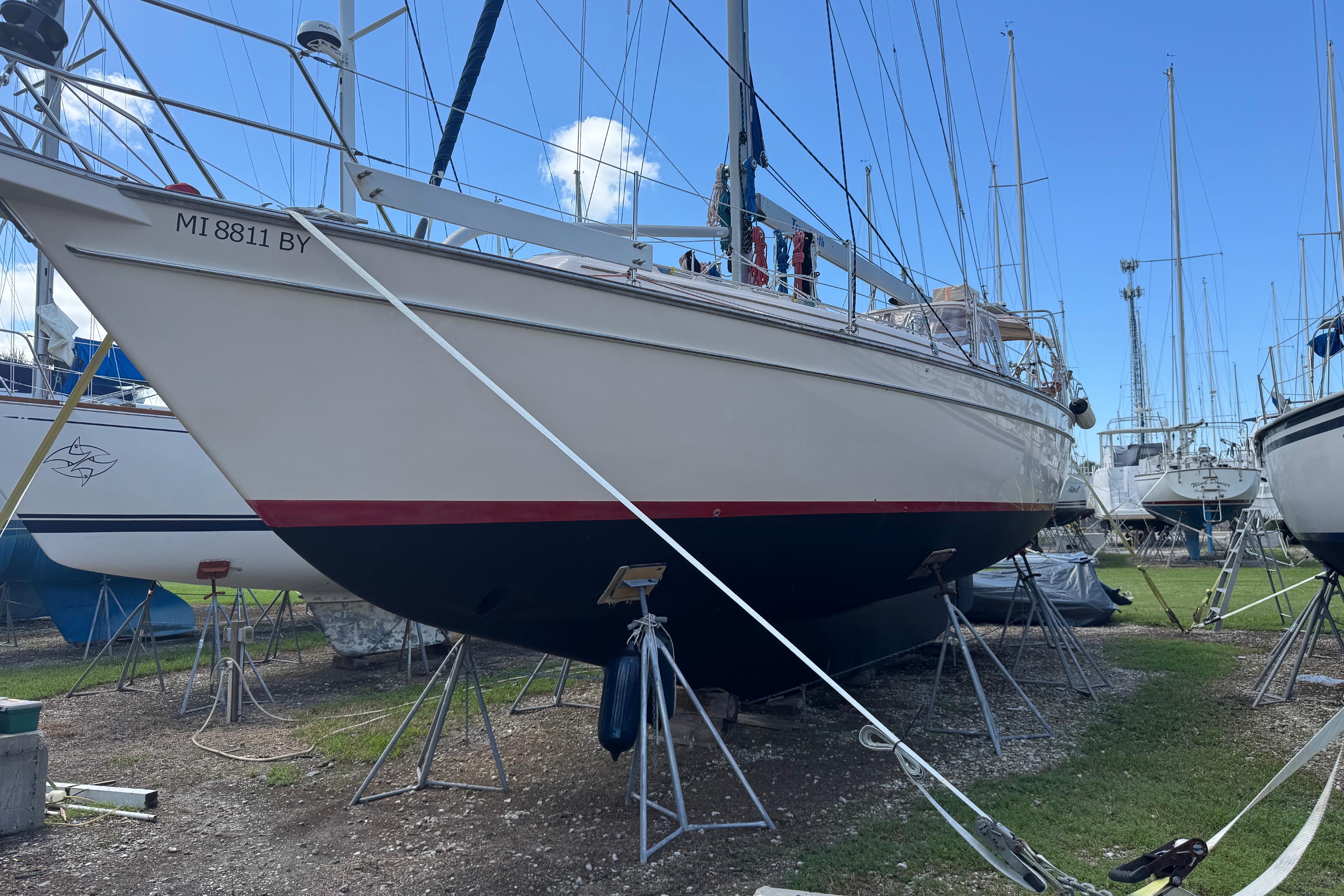 2004 Island Packet 420 sailboat on stands in a boatyard under clear blue sky.