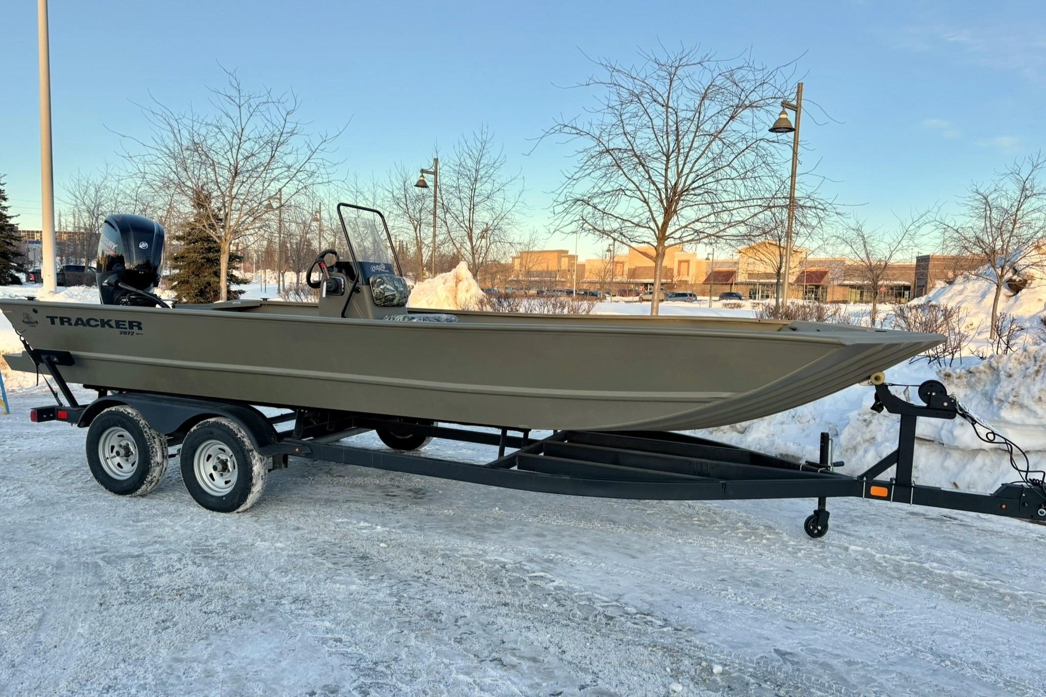 2024 Tracker Grizzly 2072 CC boat on trailer in snowy landscape.