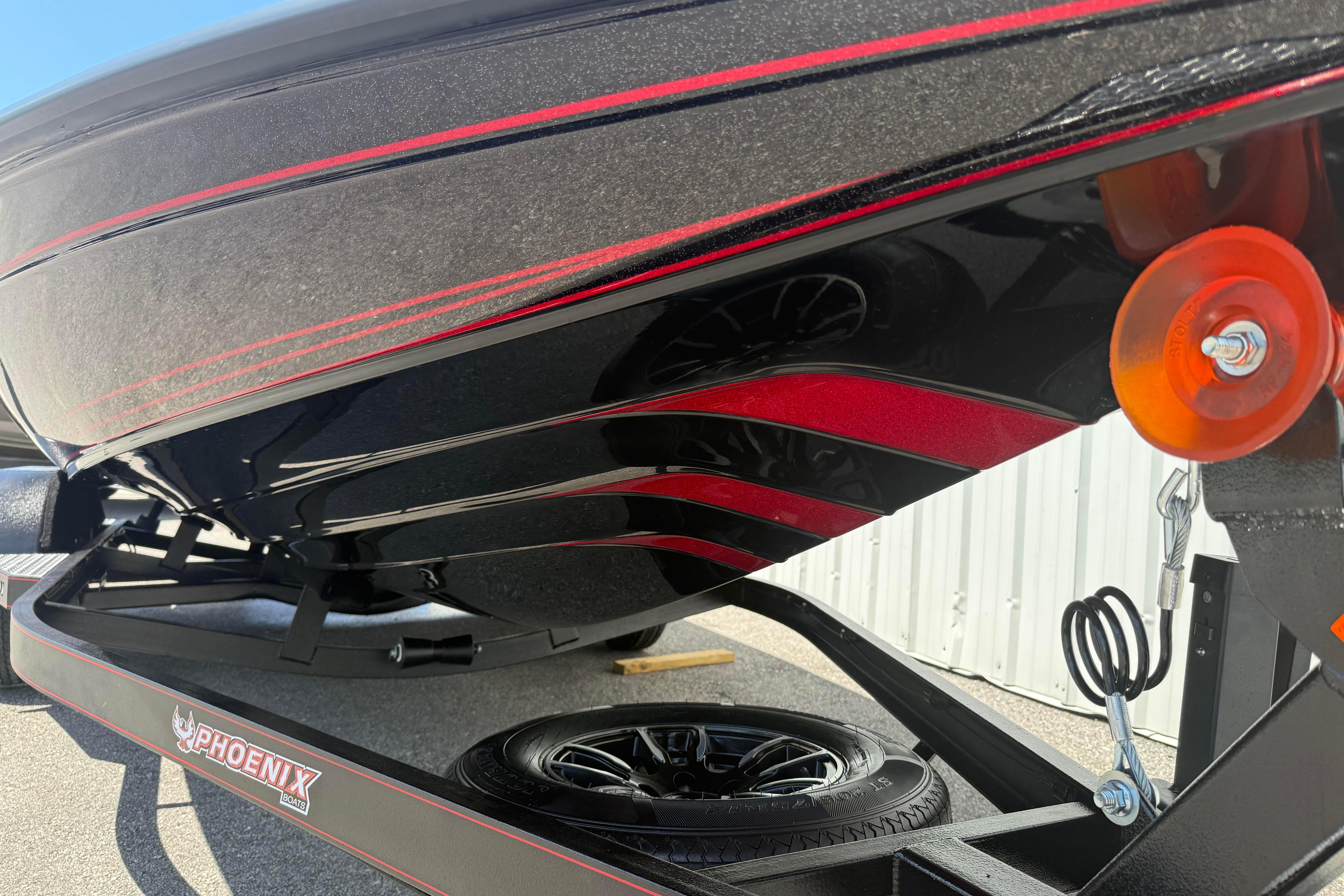 Close-up of 2027 Phoenix 919 ZXL boat hull with red accents and trailer details.