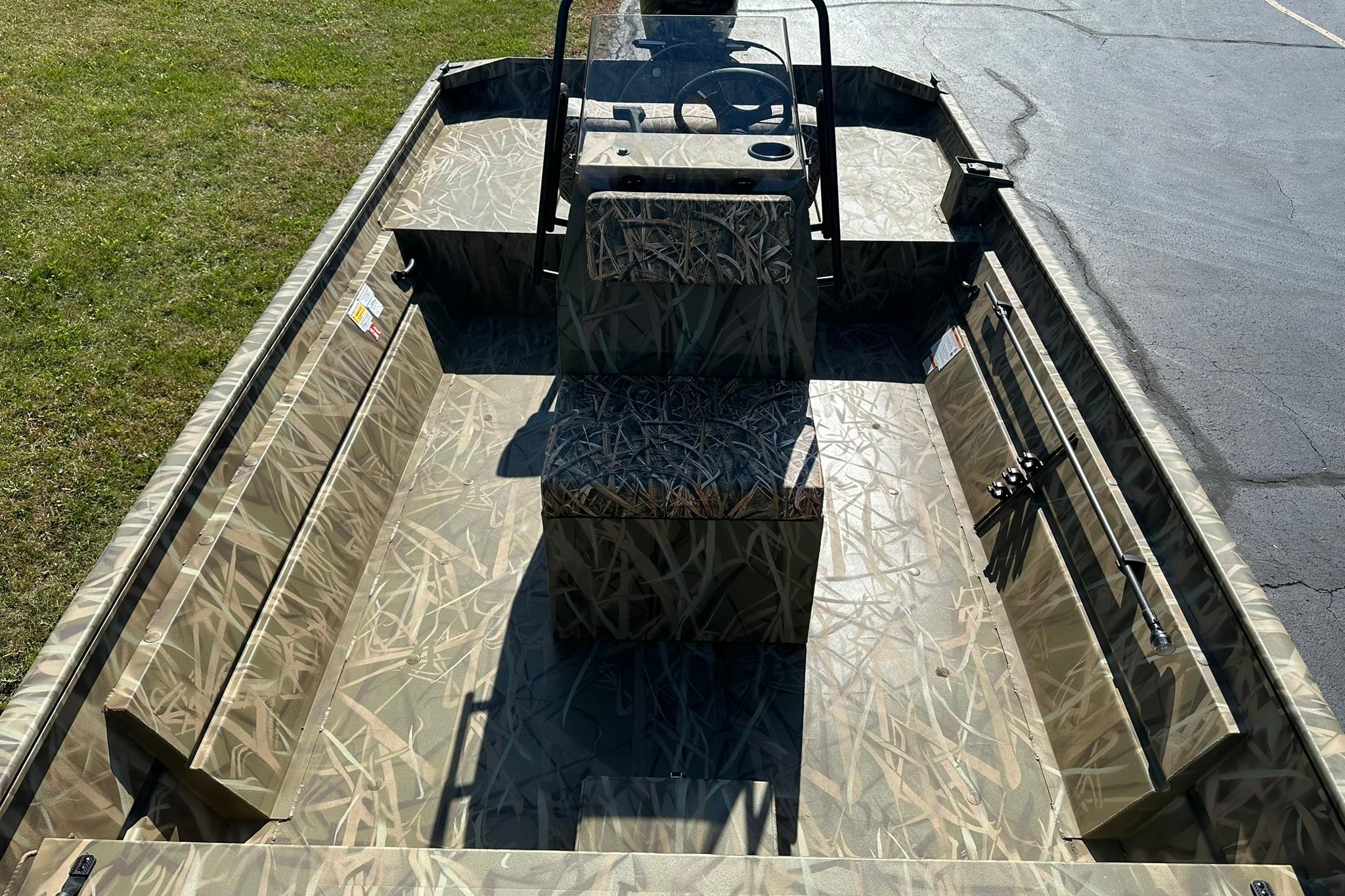 2026 Lowe Roughneck 2070CC boat with camouflage interior, parked on grass and pavement.