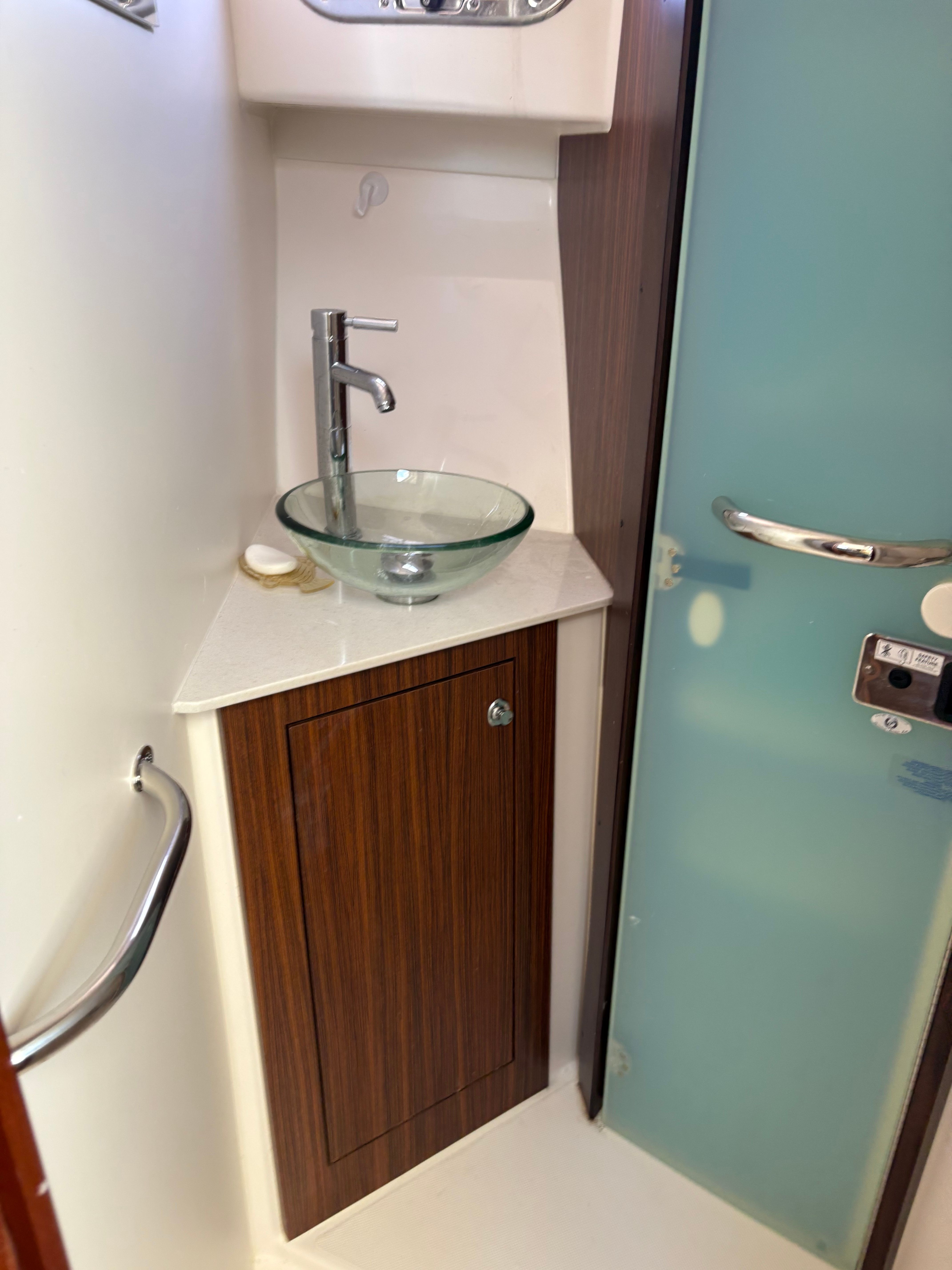 2017 Pursuit OS 355 Offshore bathroom with glass sink and wooden cabinet.