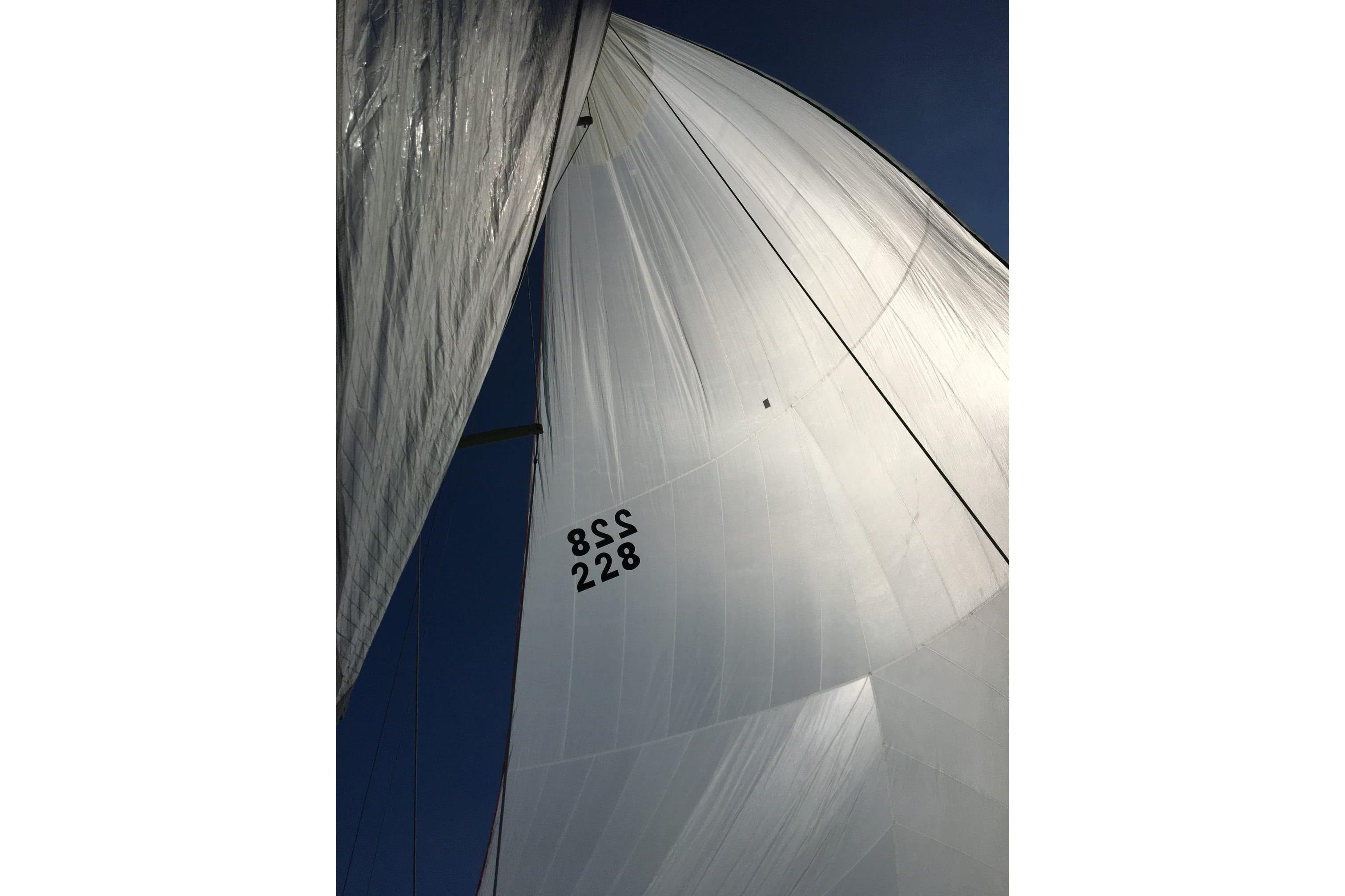 Sails of a 1991 Corsair F-27 yacht against a clear blue sky.