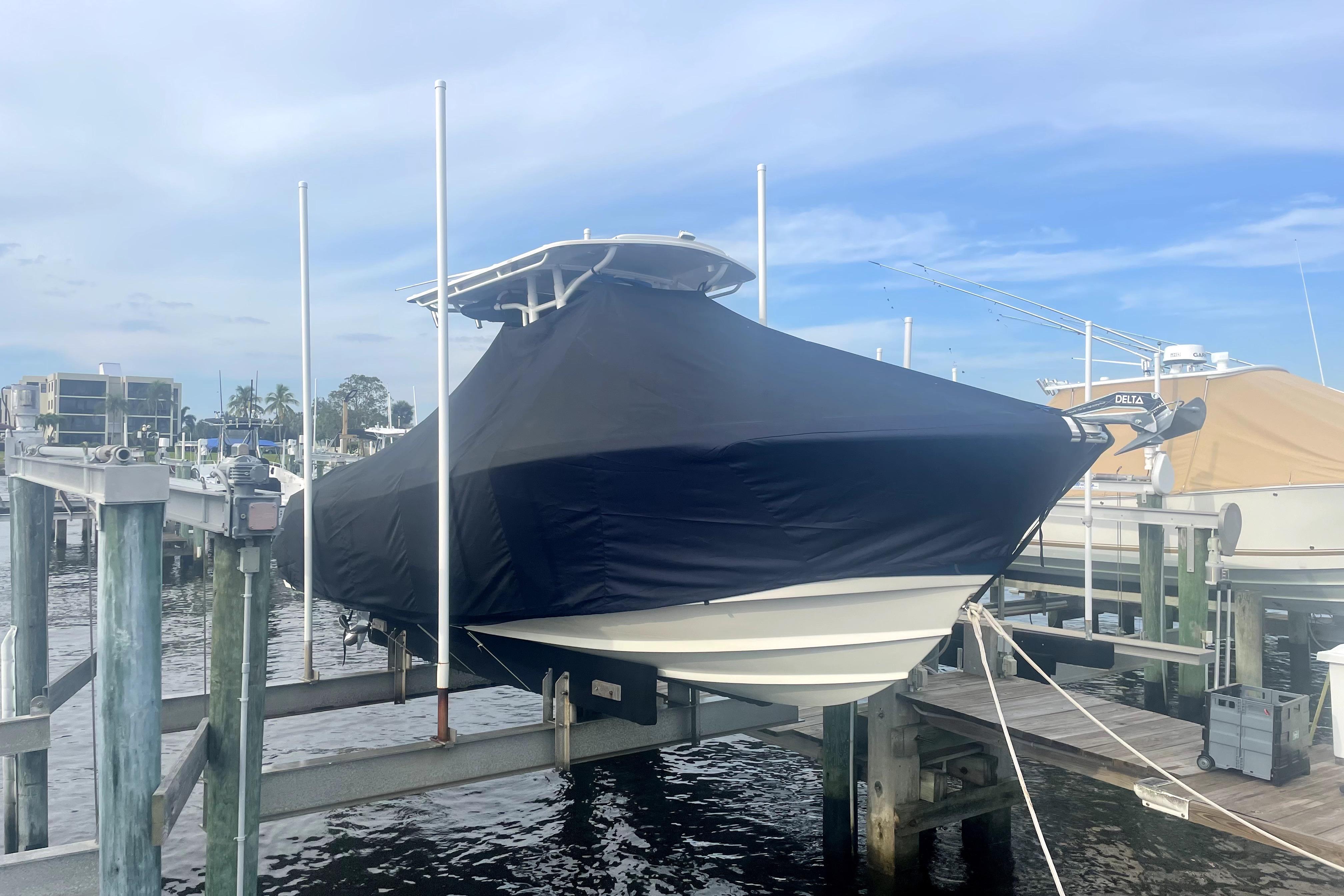 Covered 2015 Edgewater 245CC boat docked at marina under blue sky.