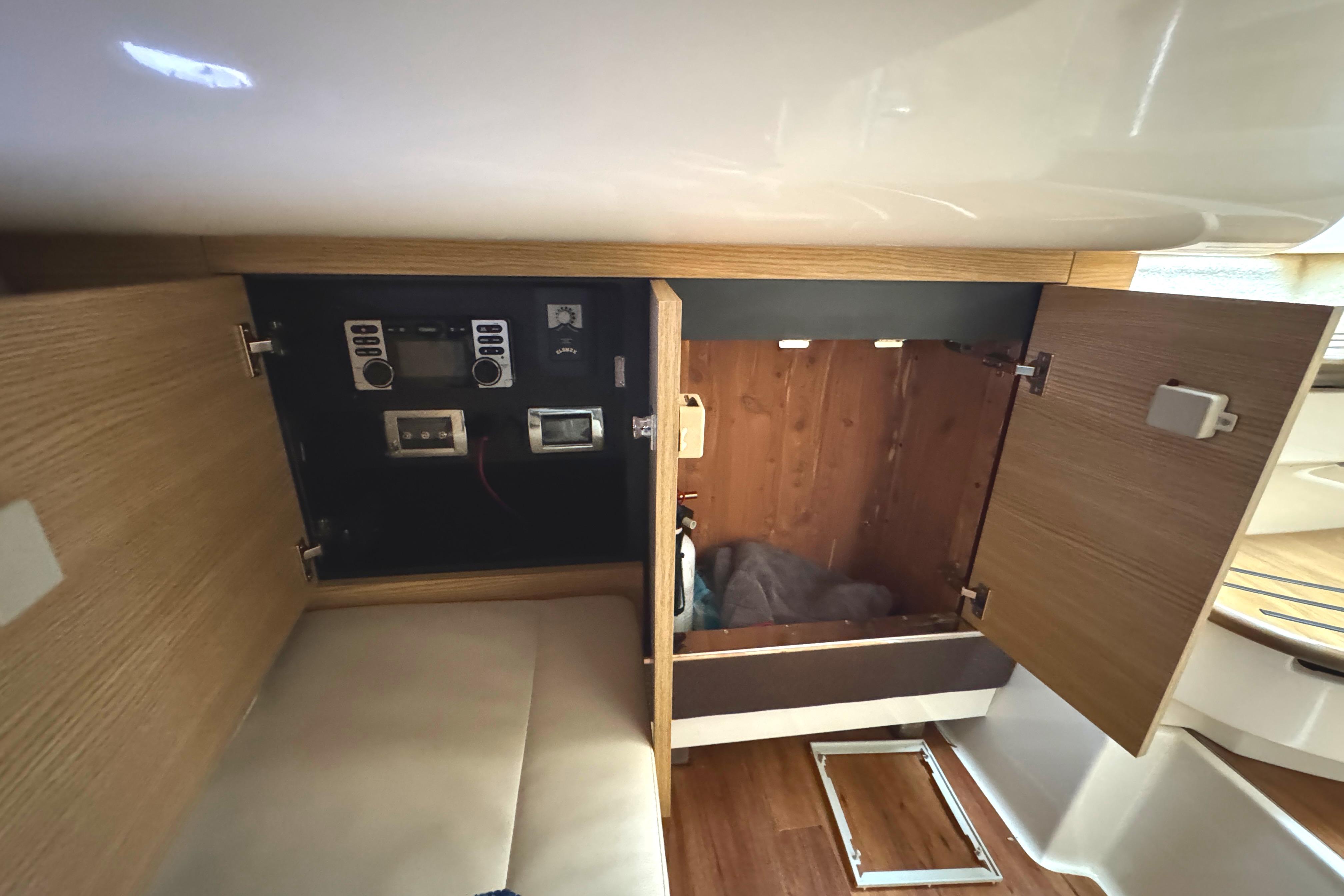 2012 Chaparral 327 SSX interior storage with open wooden cabinets and control panel.