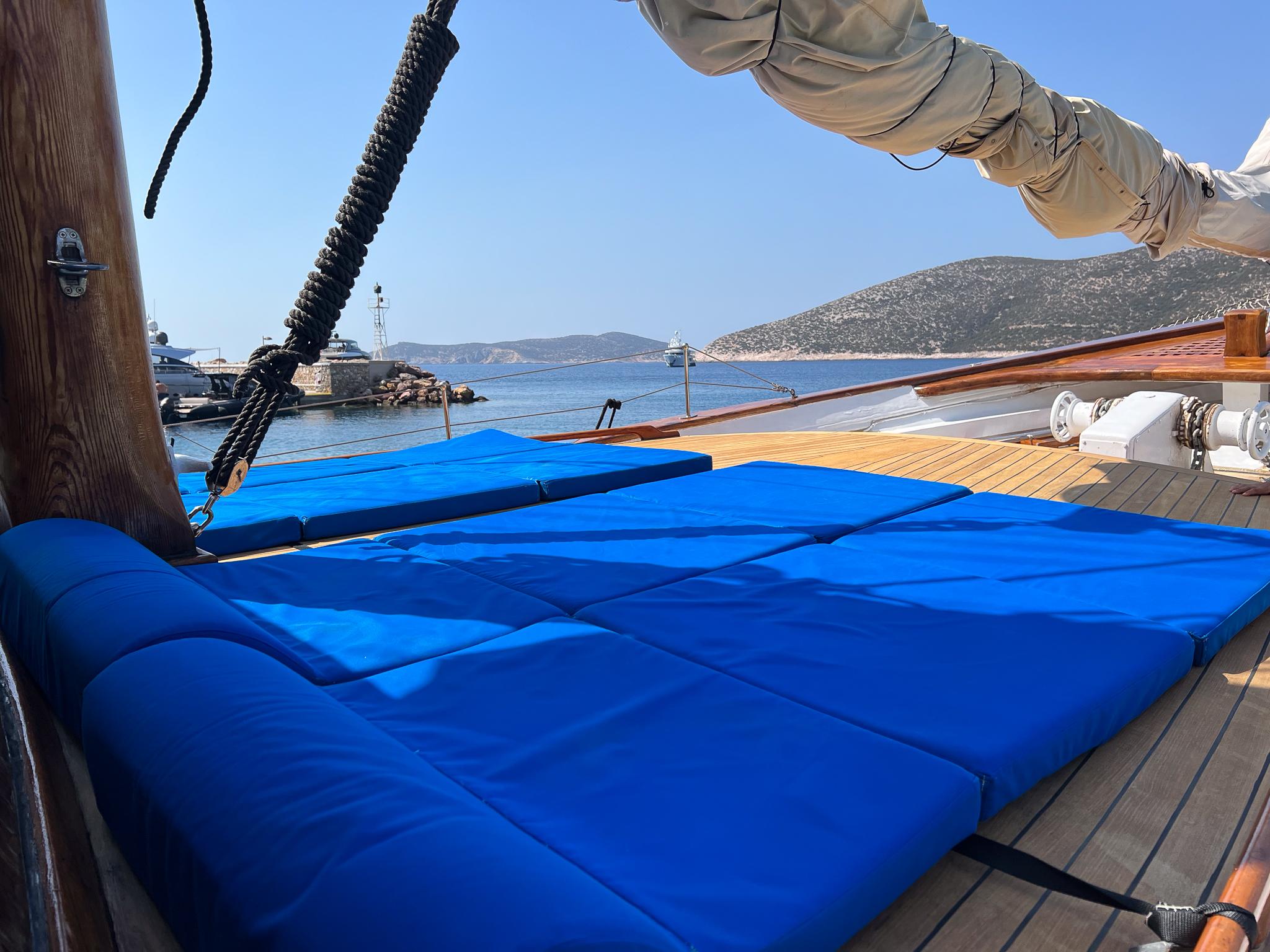 Deck of 1969 Psarros Shipyard yacht with blue cushions and scenic coastal view.